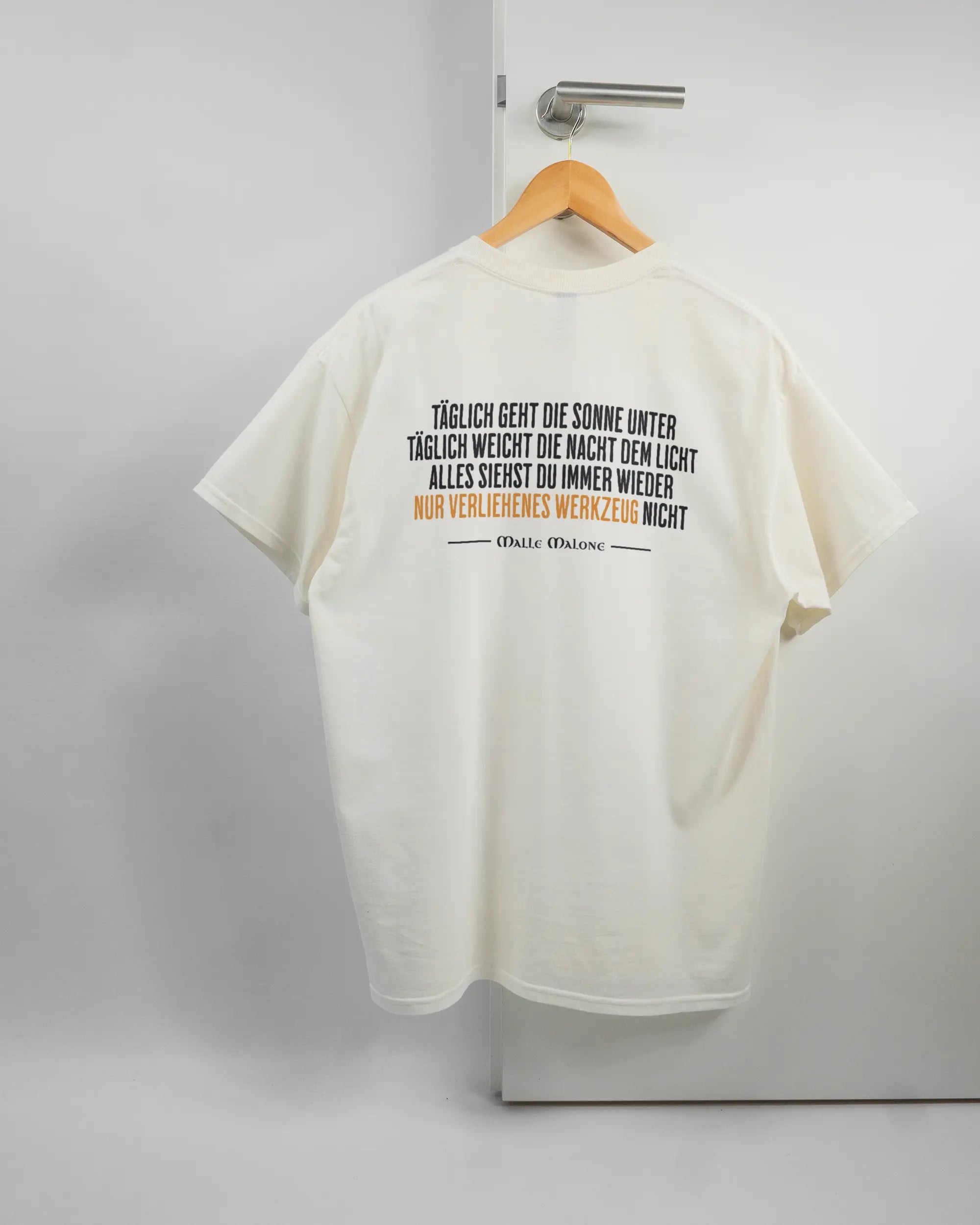 Rückseite des Basic Unisex T-Shirt Regular von Maondo mit dem Design Wegzeug in der Farbe White und in der Größe L auf einem Bügel an der Türklinke aufgehängt