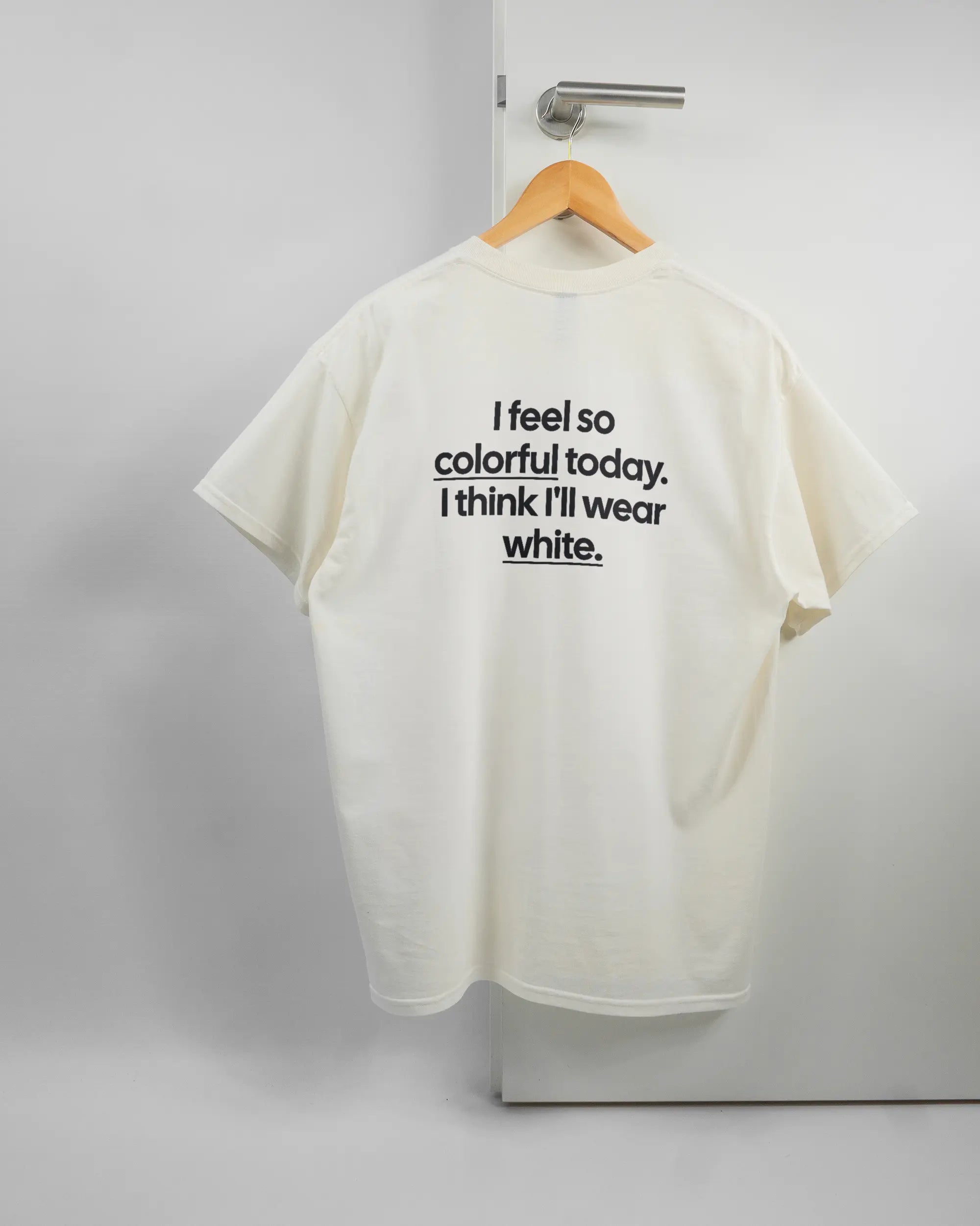 Rückseite des Basic Unisex T-Shirt Regular von Maondo mit dem Design Colorful Day in der Farbe White und in der Größe L auf einem Bügel an der Türklinke aufgehängt