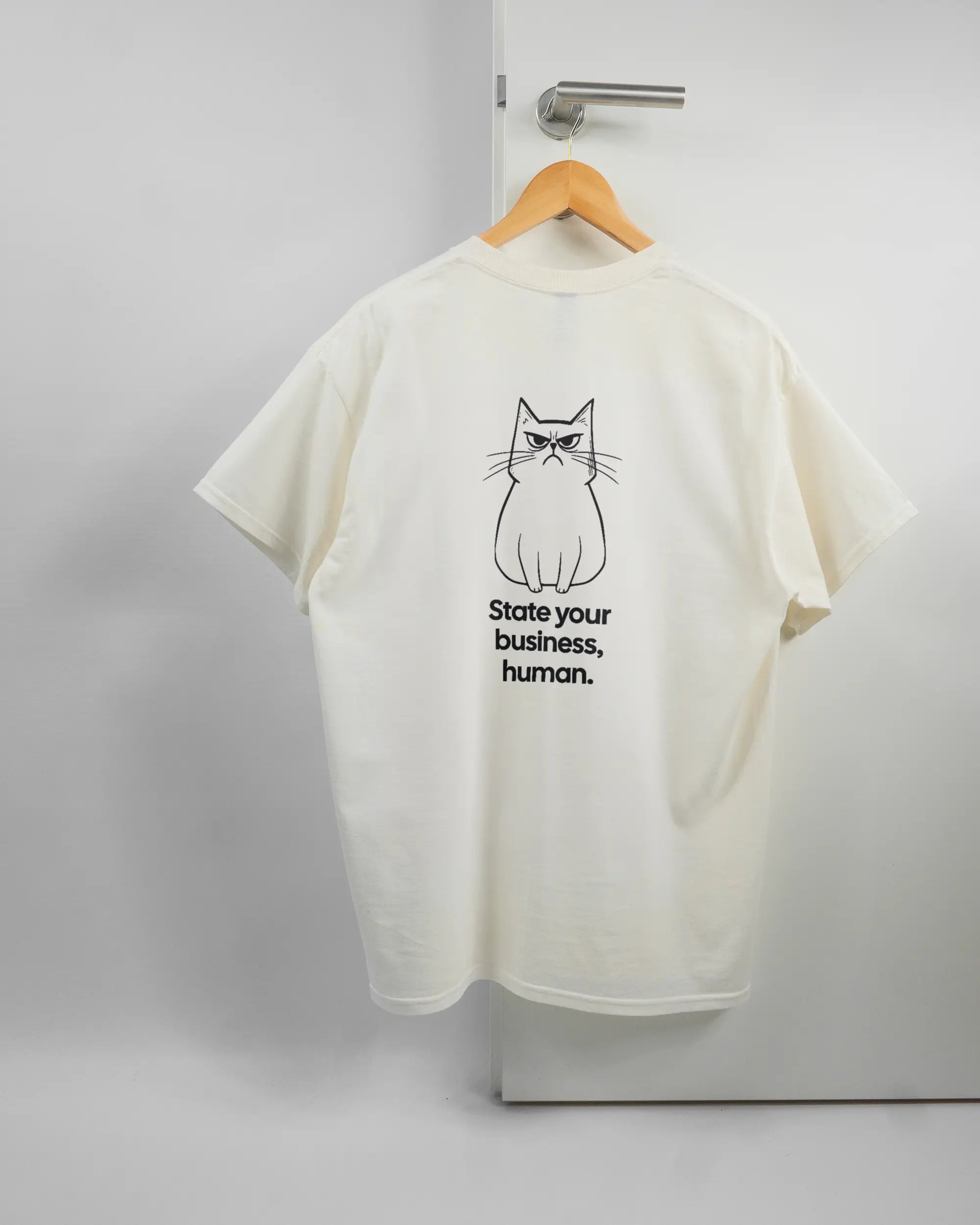 Rückseite des Basic Unisex T-Shirt Regular von Maondo mit dem Design Grumpy Purr in der Farbe White und in der Größe L auf einem Bügel an der Türklinke aufgehängt