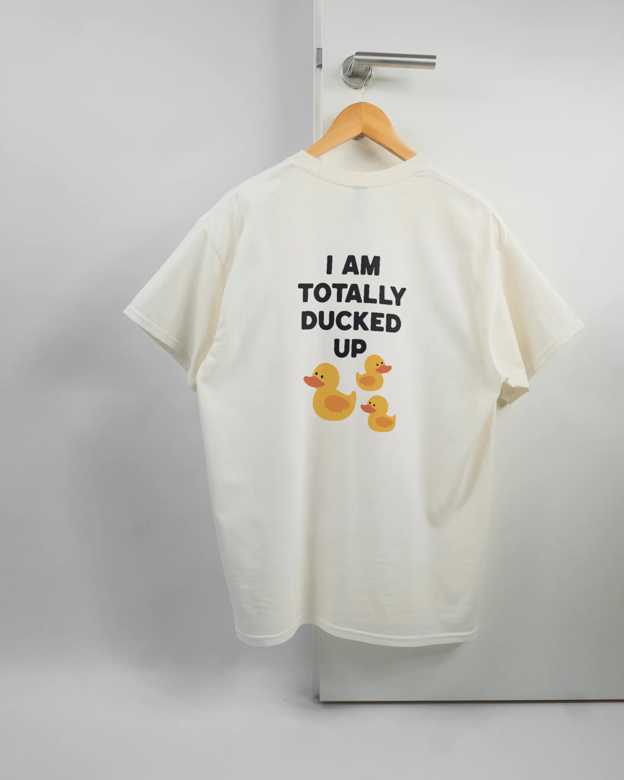 Rückseite des Basic Unisex T-Shirt Regular von Maondo mit dem Design Ducked Up in der Farbe White und in der Größe L auf einem Bügel an der Türklinke aufgehängt