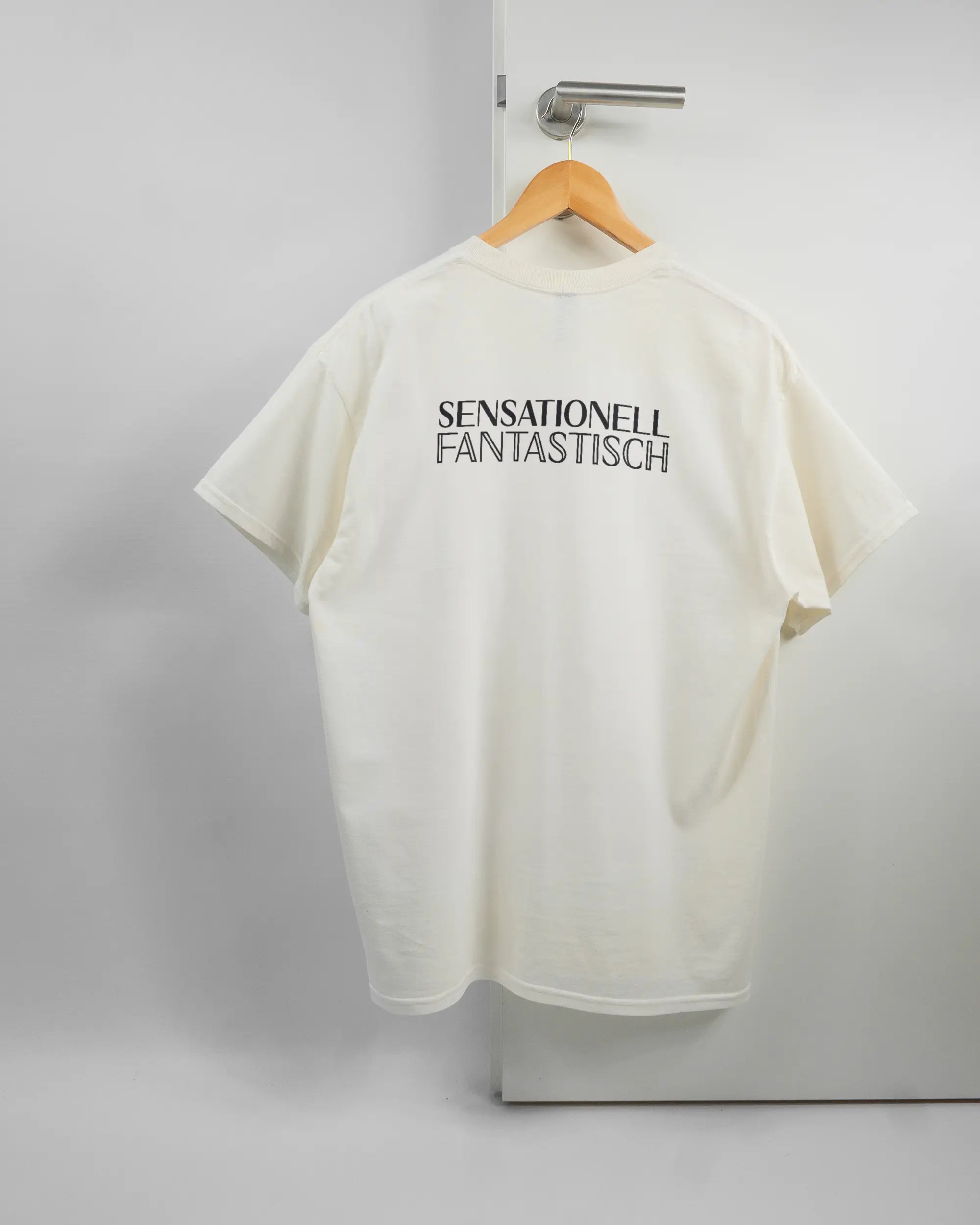 Rückseite des Basic Unisex T-Shirt Regular von Maondo mit dem Design Sensationell in der Farbe White und in der Größe L auf einem Bügel an der Türklinke aufgehängt