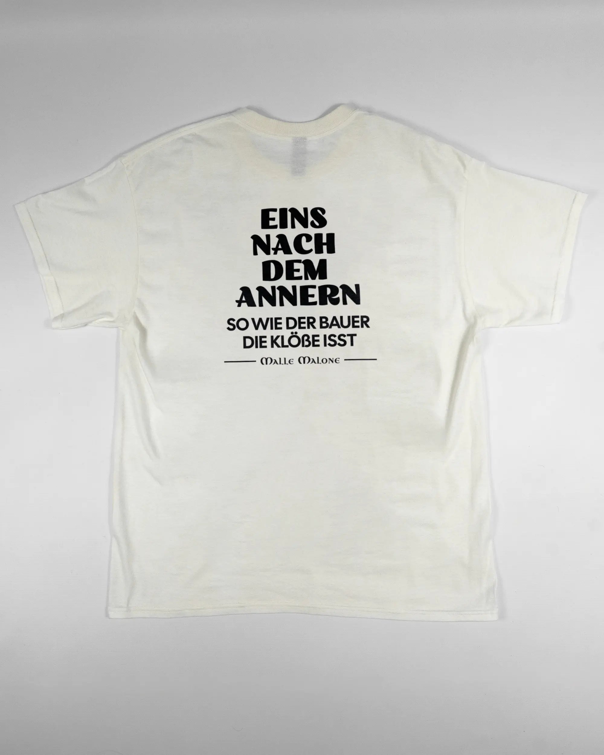 Rückseite des Basic Unisex T-Shirt Regular von Maondo mit dem Design Eins nach dem Annern in der Farbe White und in der Größe L flach auf den Boden gelegt