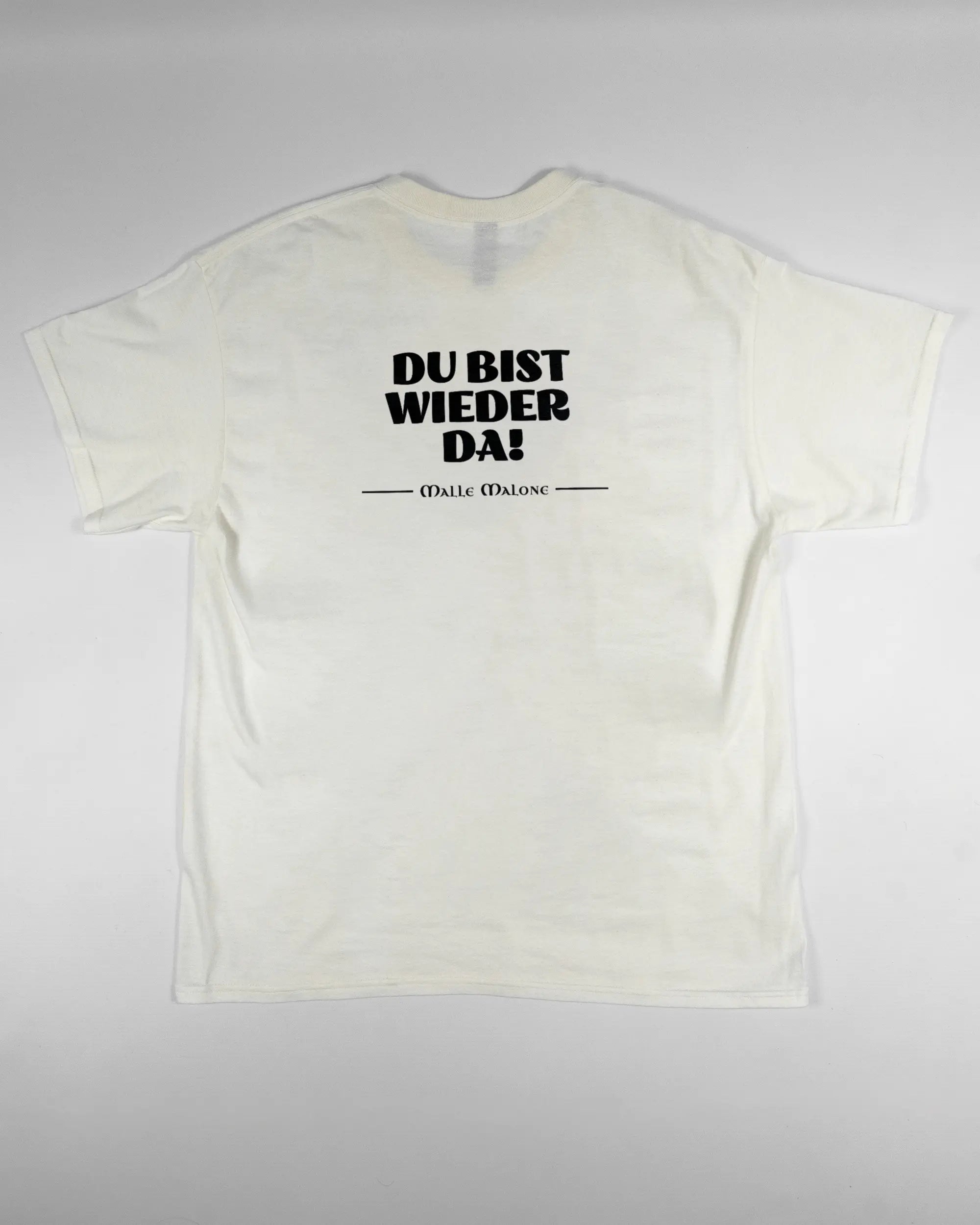 Rückseite des Basic Unisex T-Shirt Regular von Maondo mit dem Design Wieder da in der Farbe White und in der Größe L flach auf den Boden gelegt
