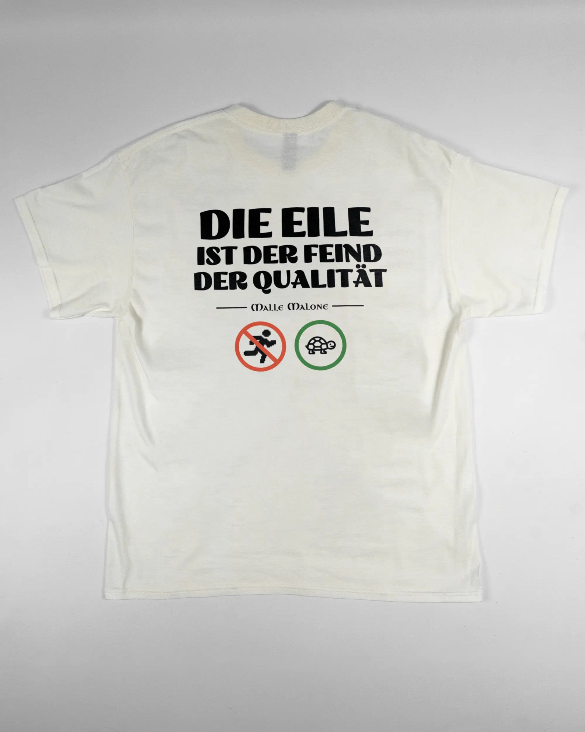 Rückseite des Basic Unisex T-Shirt Regular von Maondo mit dem Design Keine Eile in der Farbe White und in der Größe L flach auf den Boden gelegt