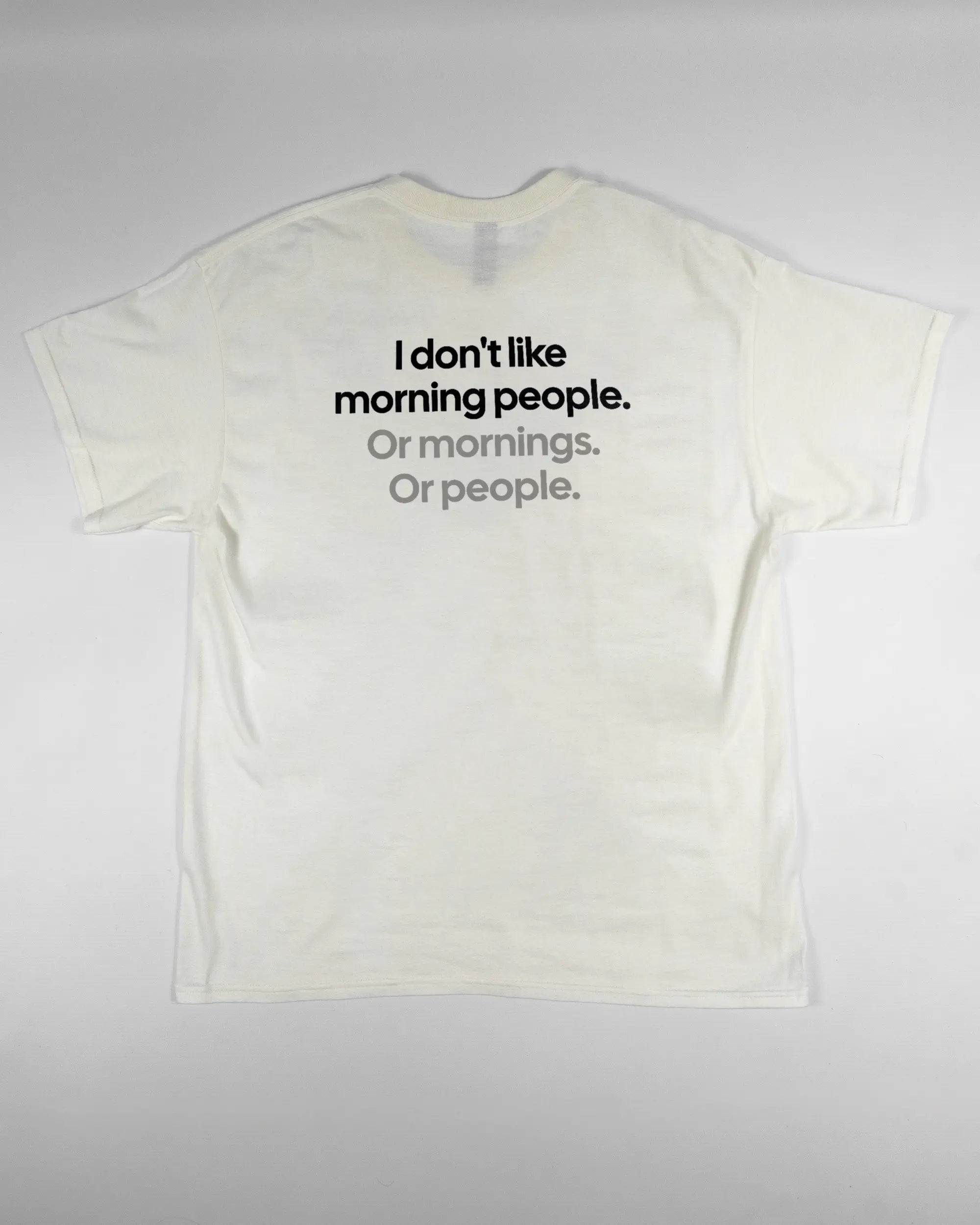 Rückseite des Basic Unisex T-Shirt Regular von Maondo mit dem Design Morning Person in der Farbe White und in der Größe L flach auf den Boden gelegt