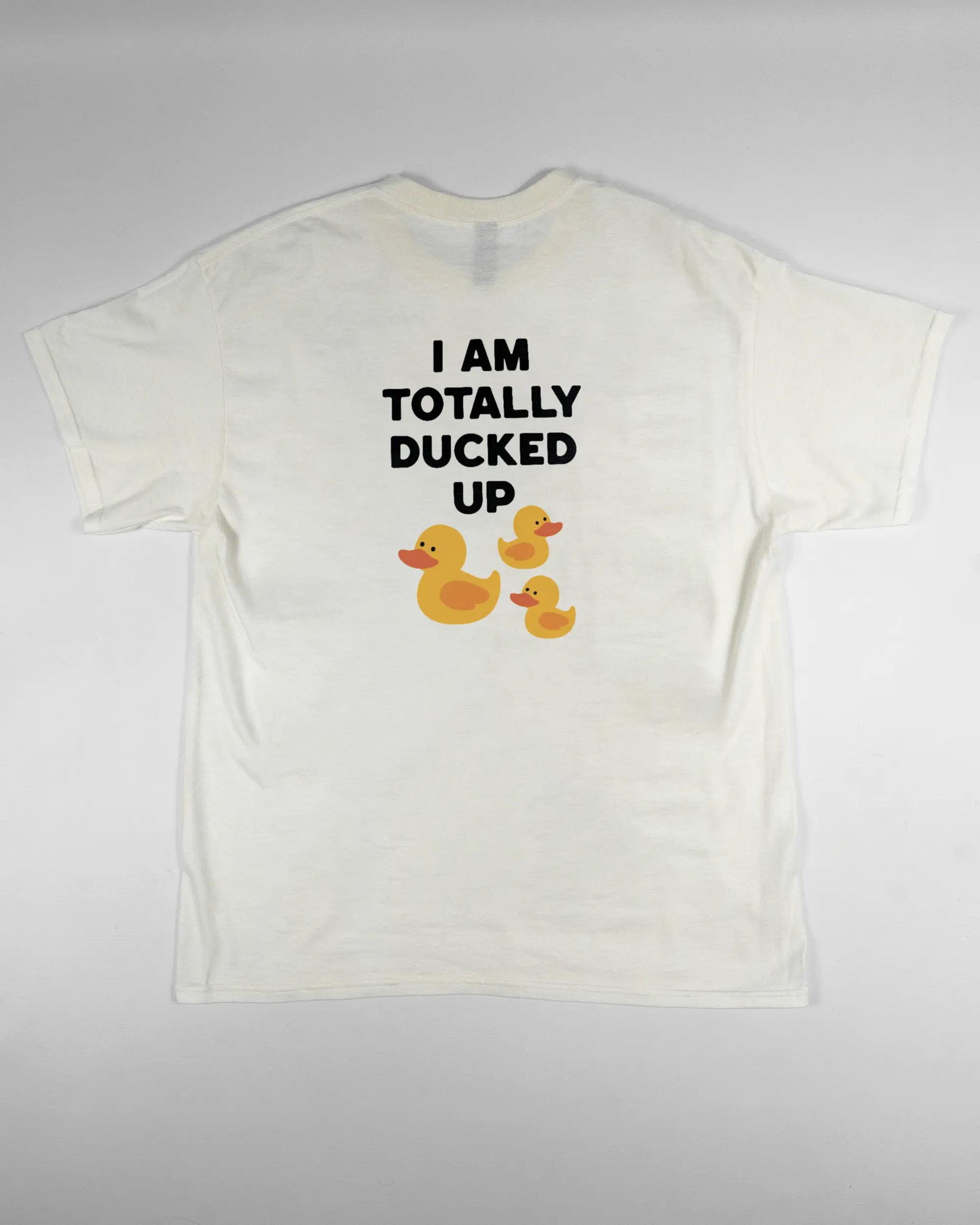 Rückseite des Basic Unisex T-Shirt Regular von Maondo mit dem Design Ducked Up in der Farbe White und in der Größe L flach auf den Boden gelegt