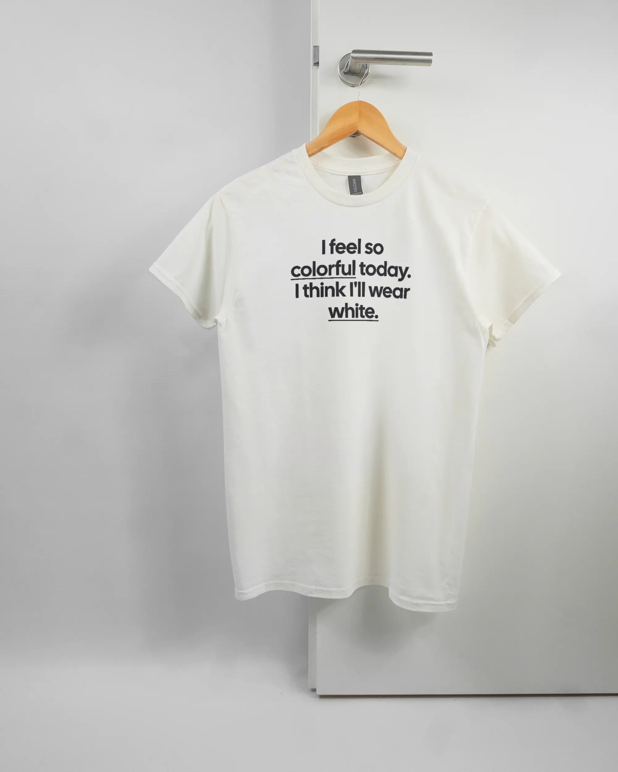 Vorderseite des Basic Unisex T-Shirt Regular von Maondo mit dem Design Colorful Day in der Farbe White und in der Größe S auf einem Bügel an der Türklinke aufgehängt