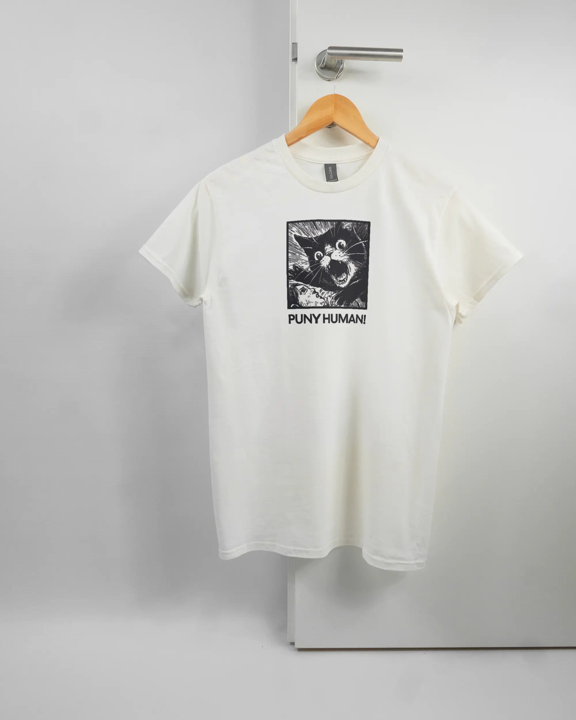 Vorderseite des Basic Unisex T-Shirt Regular von Maondo mit dem Design Puny Human in der Farbe White und in der Größe S auf einem Bügel an der Türklinke aufgehängt
