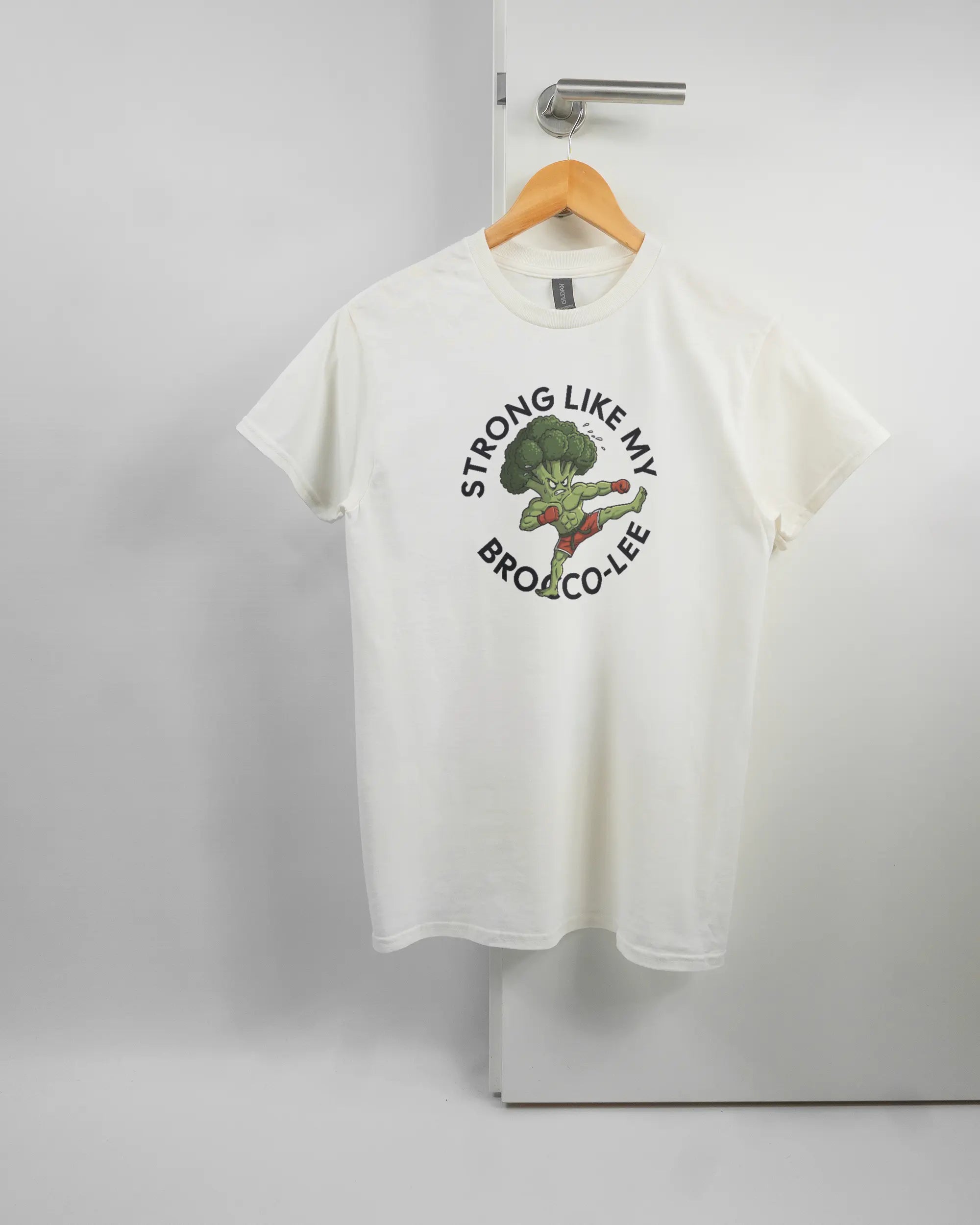 Vorderseite des Basic Unisex T-Shirt Regular von Maondo mit dem Design Brocco-Lee in der Farbe White und in der Größe S auf einem Bügel an der Türklinke aufgehängt