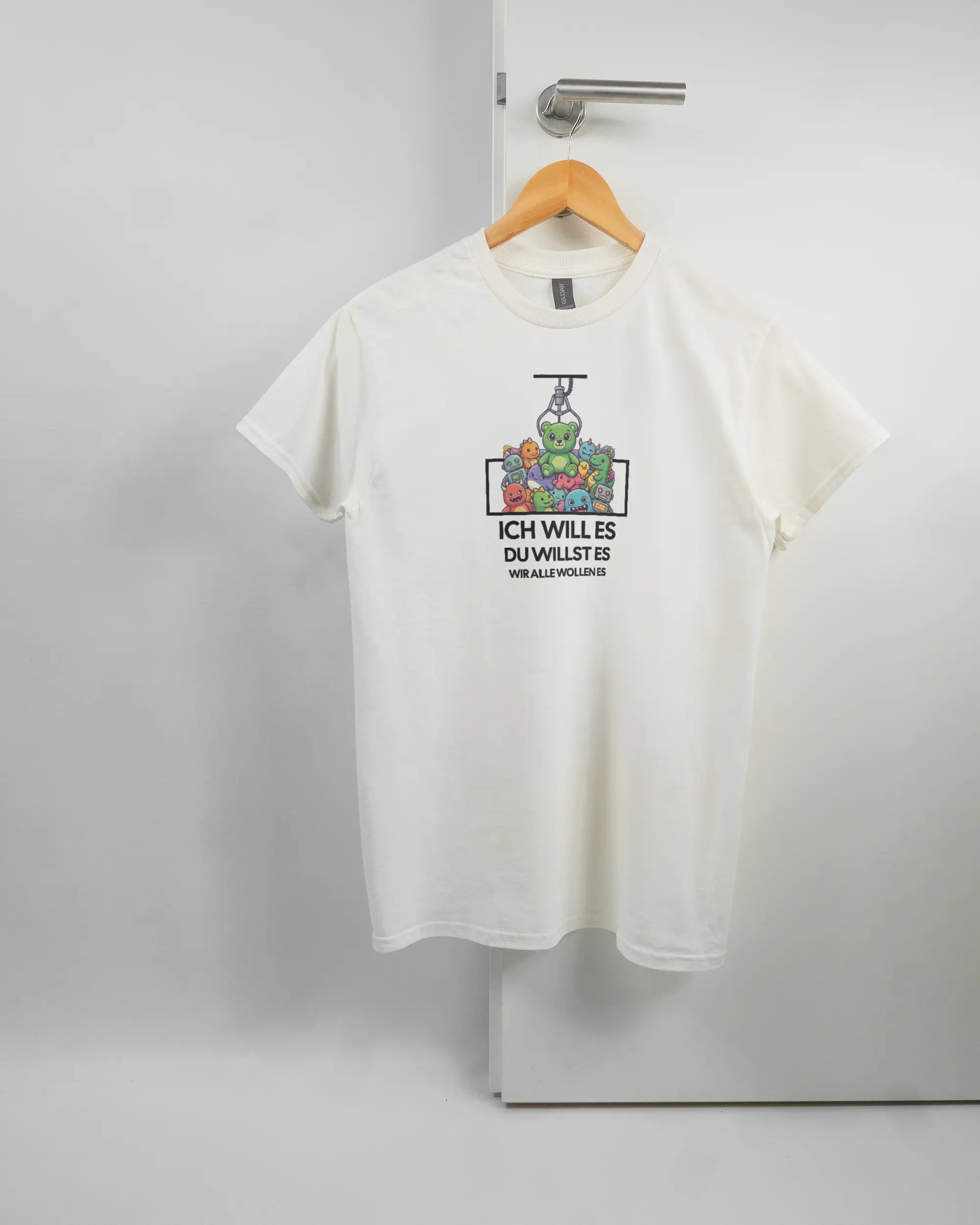 Vorderseite des Basic Unisex T-Shirt Regular von Maondo mit dem Design Will Stofftier in der Farbe White und in der Größe S auf einem Bügel an der Türklinke aufgehängt