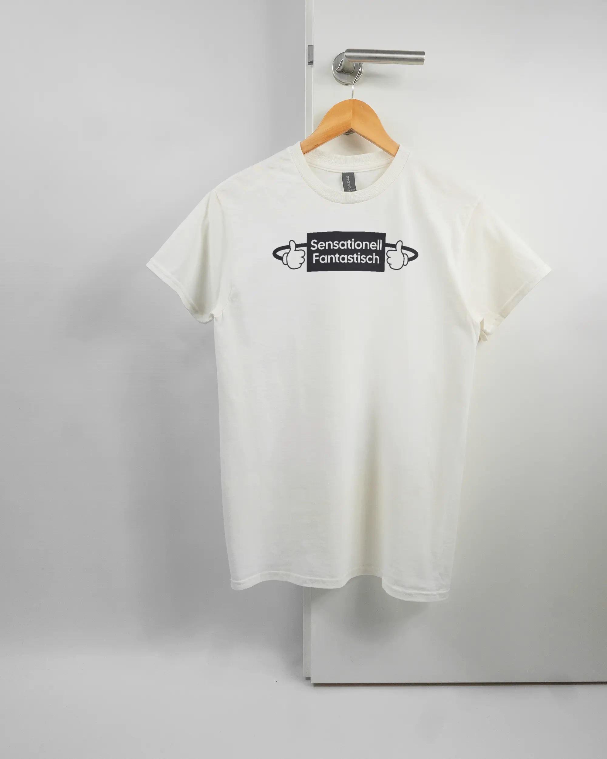 Vorderseite des Basic Unisex T-Shirt Regular von Maondo mit dem Design Fantastisch in der Farbe White und in der Größe S auf einem Bügel an der Türklinke aufgehängt