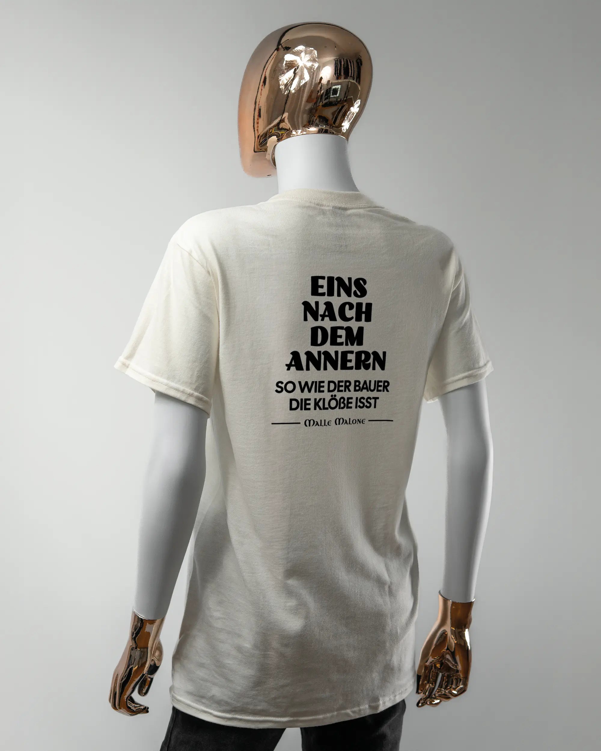 Rückseite des Basic Unisex T-Shirt Regular von Maondo mit dem Design Eins nach dem Annern in der Farbe White und in der Größe S getragen von einer femininen Puppe