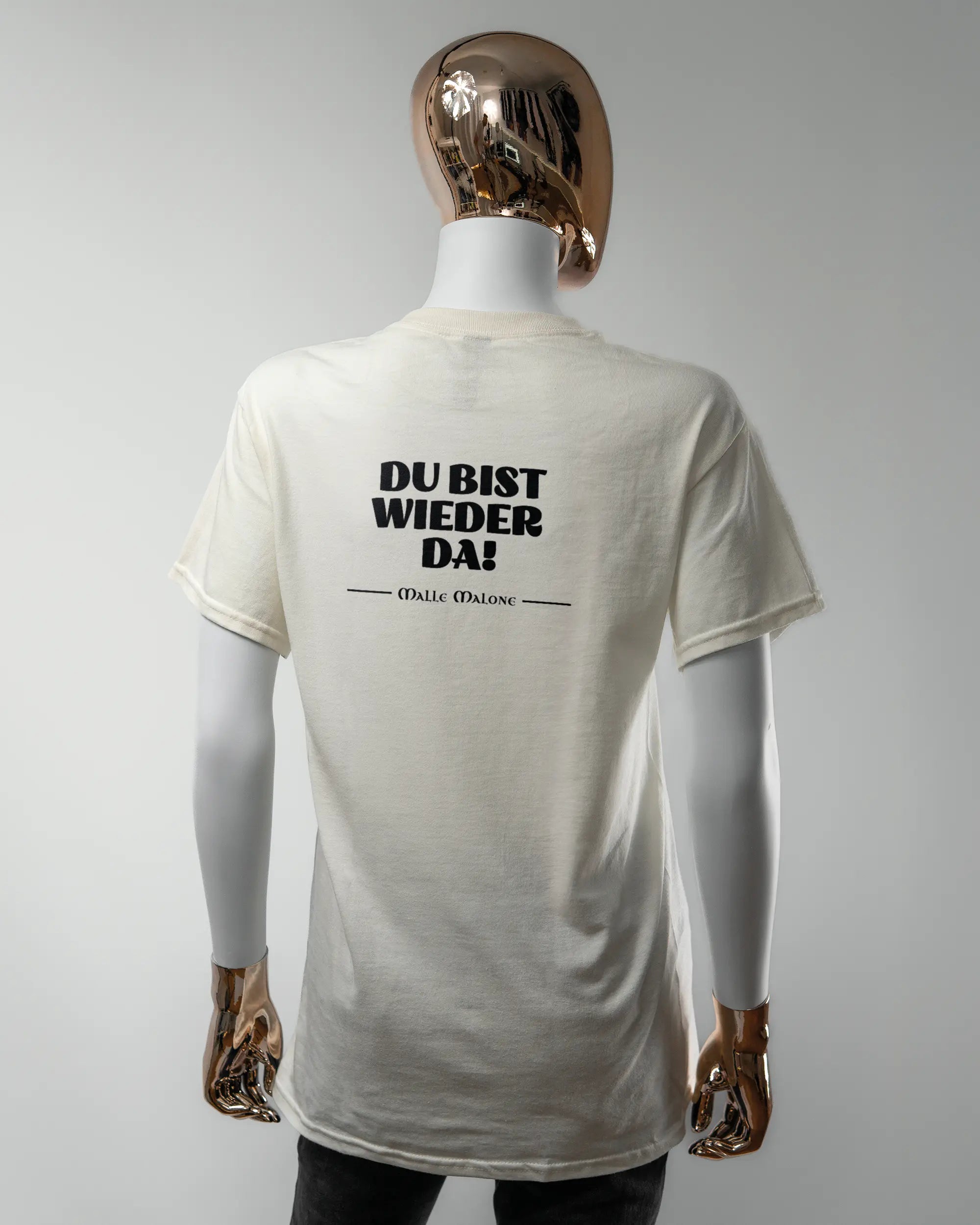 Rückseite des Basic Unisex T-Shirt Regular von Maondo mit dem Design Wieder da in der Farbe White und in der Größe S getragen von einer femininen Puppe