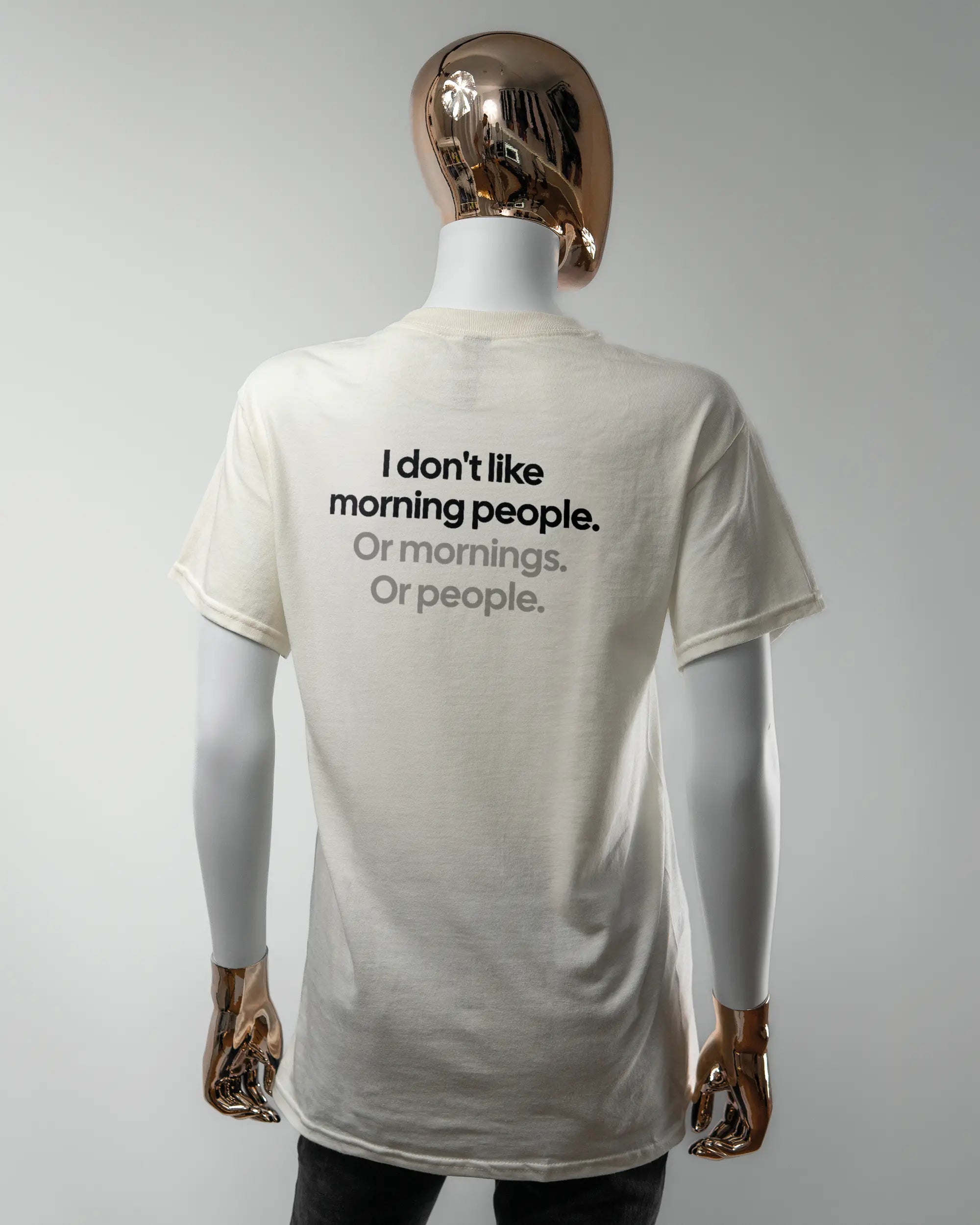 Rückseite des Basic Unisex T-Shirt Regular von Maondo mit dem Design Morning Person in der Farbe White und in der Größe S getragen von einer femininen Puppe