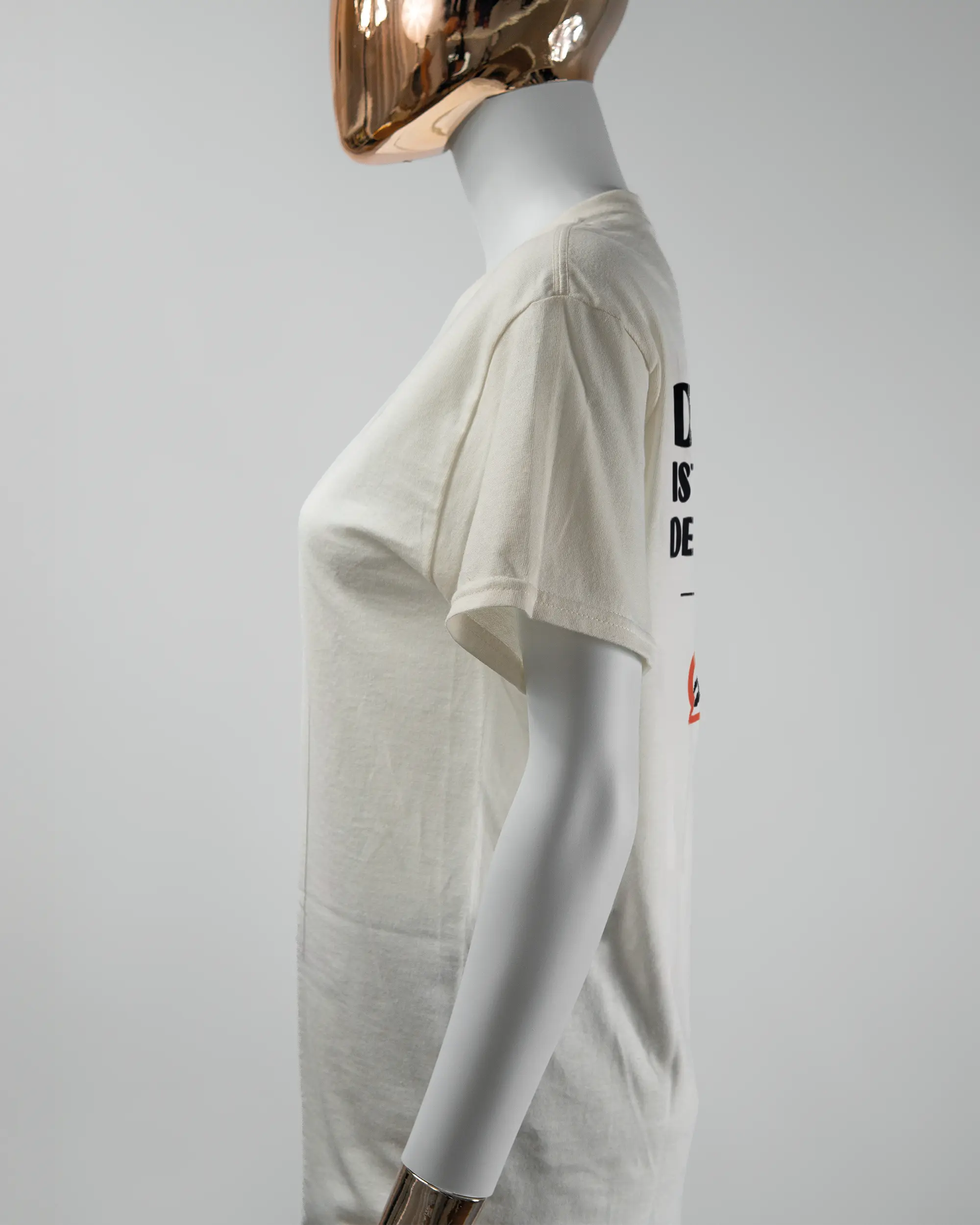 Seitenansicht des Basic Unisex T-Shirt Regular von Maondo mit dem Design Keine Eile hinten in der Farbe White und in der Größe S getragen von einer femininen Puppe