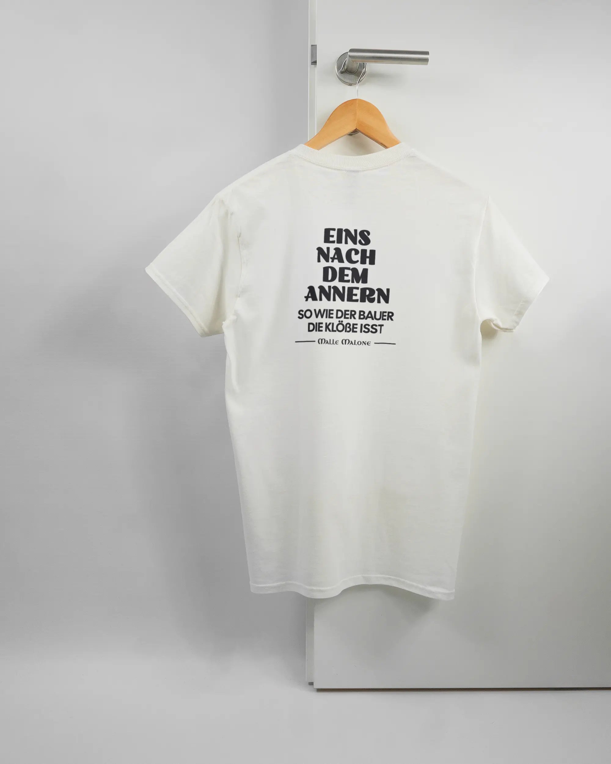Rückseite des Basic Unisex T-Shirt Regular von Maondo mit dem Design Eins nach dem Annern in der Farbe White und in der Größe S auf einem Bügel an der Türklinke aufgehängt