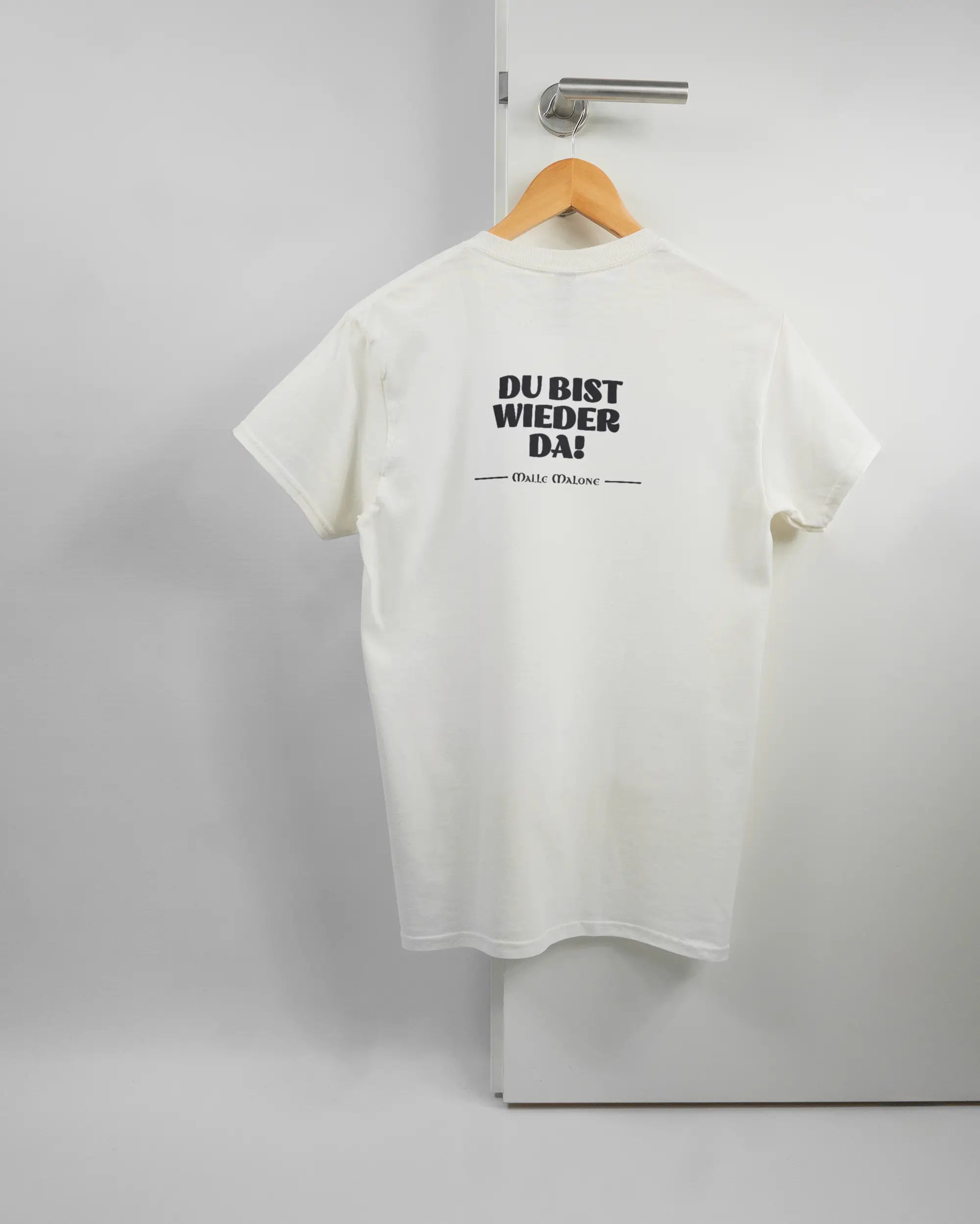 Rückseite des Basic Unisex T-Shirt Regular von Maondo mit dem Design Wieder da in der Farbe White und in der Größe S auf einem Bügel an der Türklinke aufgehängt