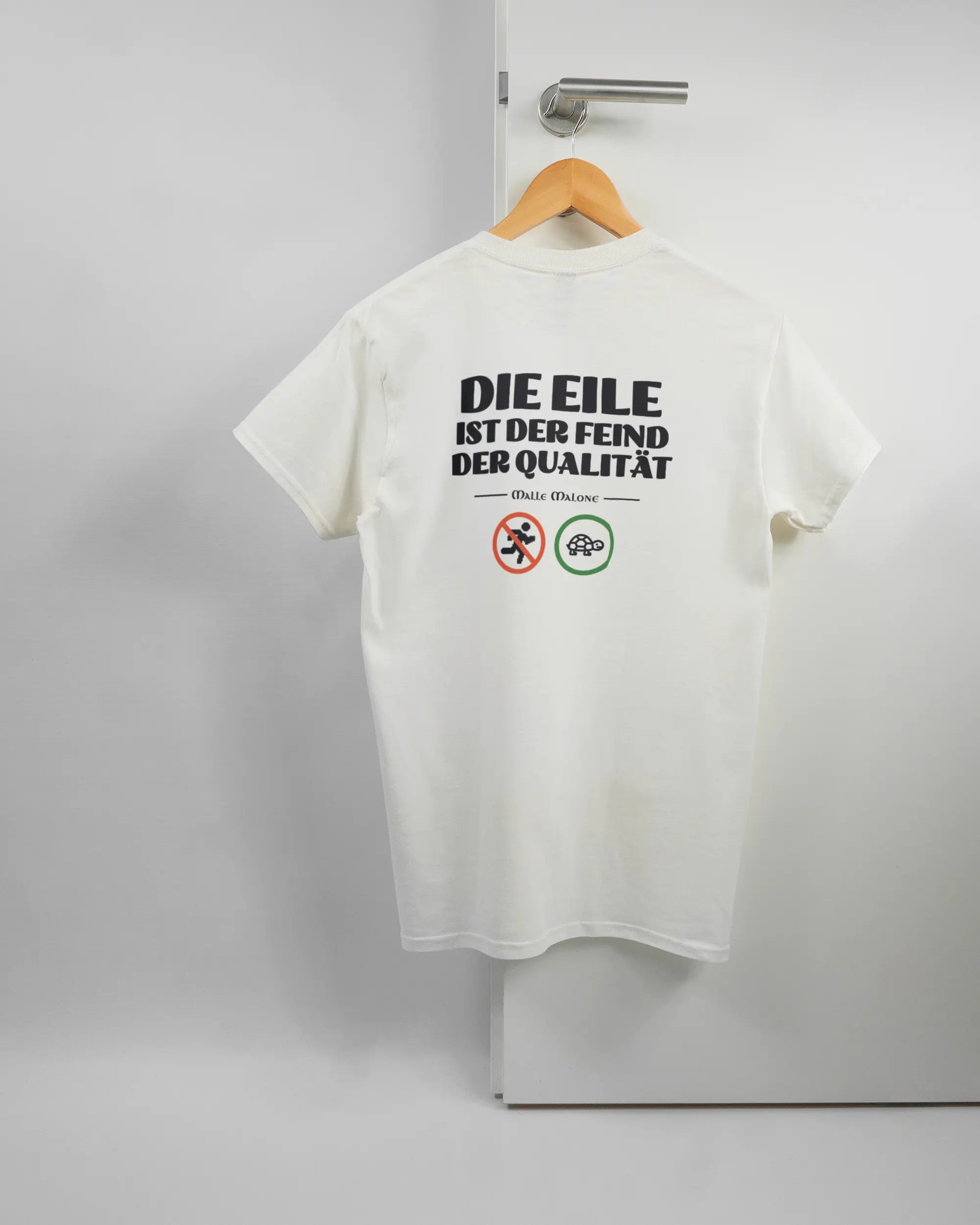 Rückseite des Basic Unisex T-Shirt Regular von Maondo mit dem Design Keine Eile in der Farbe White und in der Größe S auf einem Bügel an der Türklinke aufgehängt