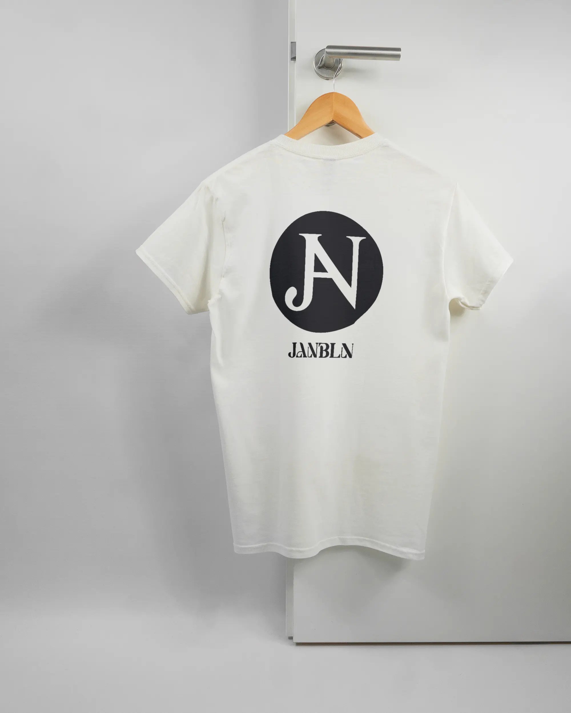 Rückseite des Basic Unisex T-Shirt Regular von Maondo mit dem Design JB1 in der Farbe White und in der Größe S auf einem Bügel an der Türklinke aufgehängt