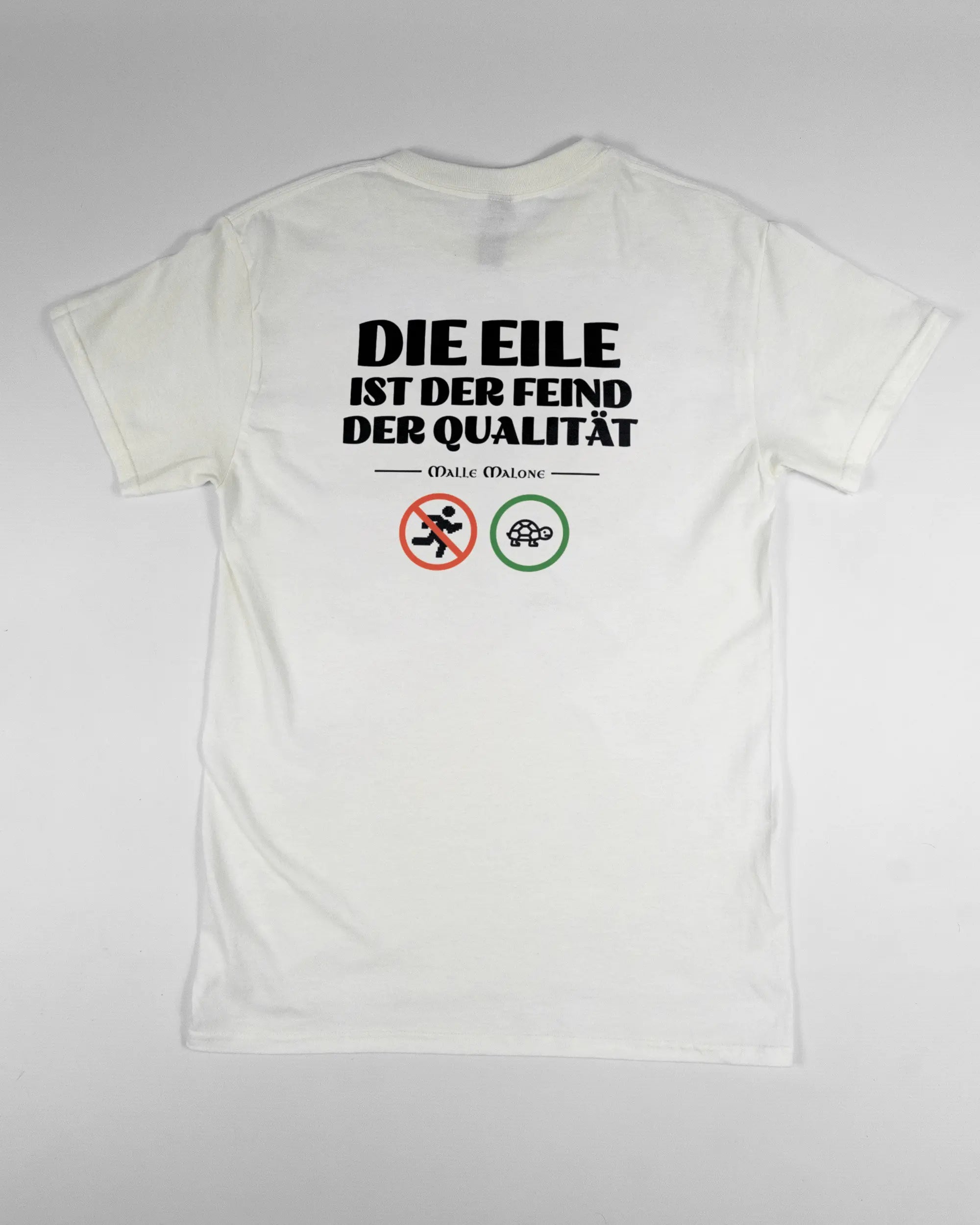 Rückseite des Basic Unisex T-Shirt Regular von Maondo mit dem Design Keine Eile in der Farbe White und in der Größe S flach auf den Boden gelegt