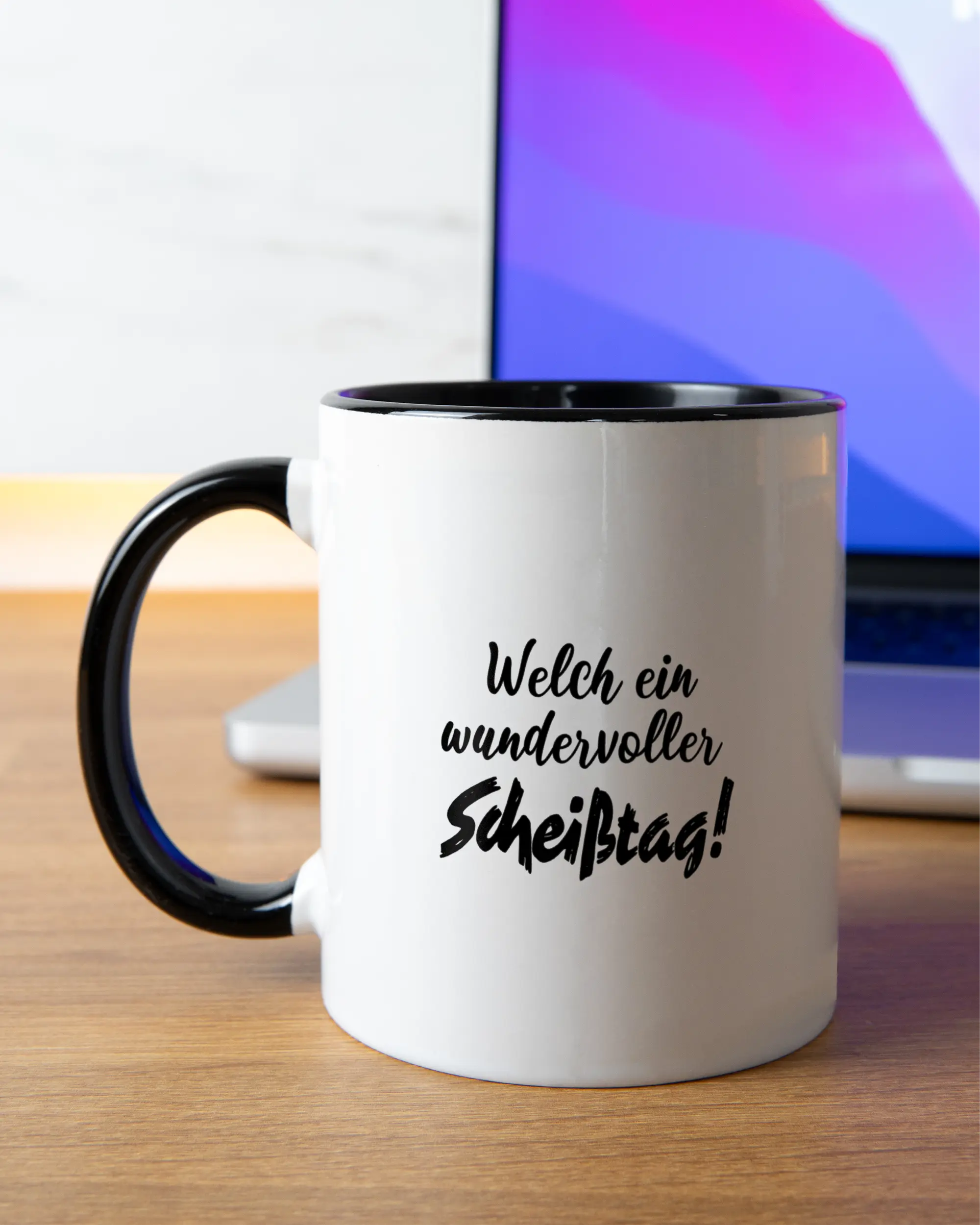 Homeoffice Aufnahme der beidseitig bedruckten Keramik Tasse von Maondo mit dem Design Wundervoller Scheißtag in der Farbe Schwarz-Weiß