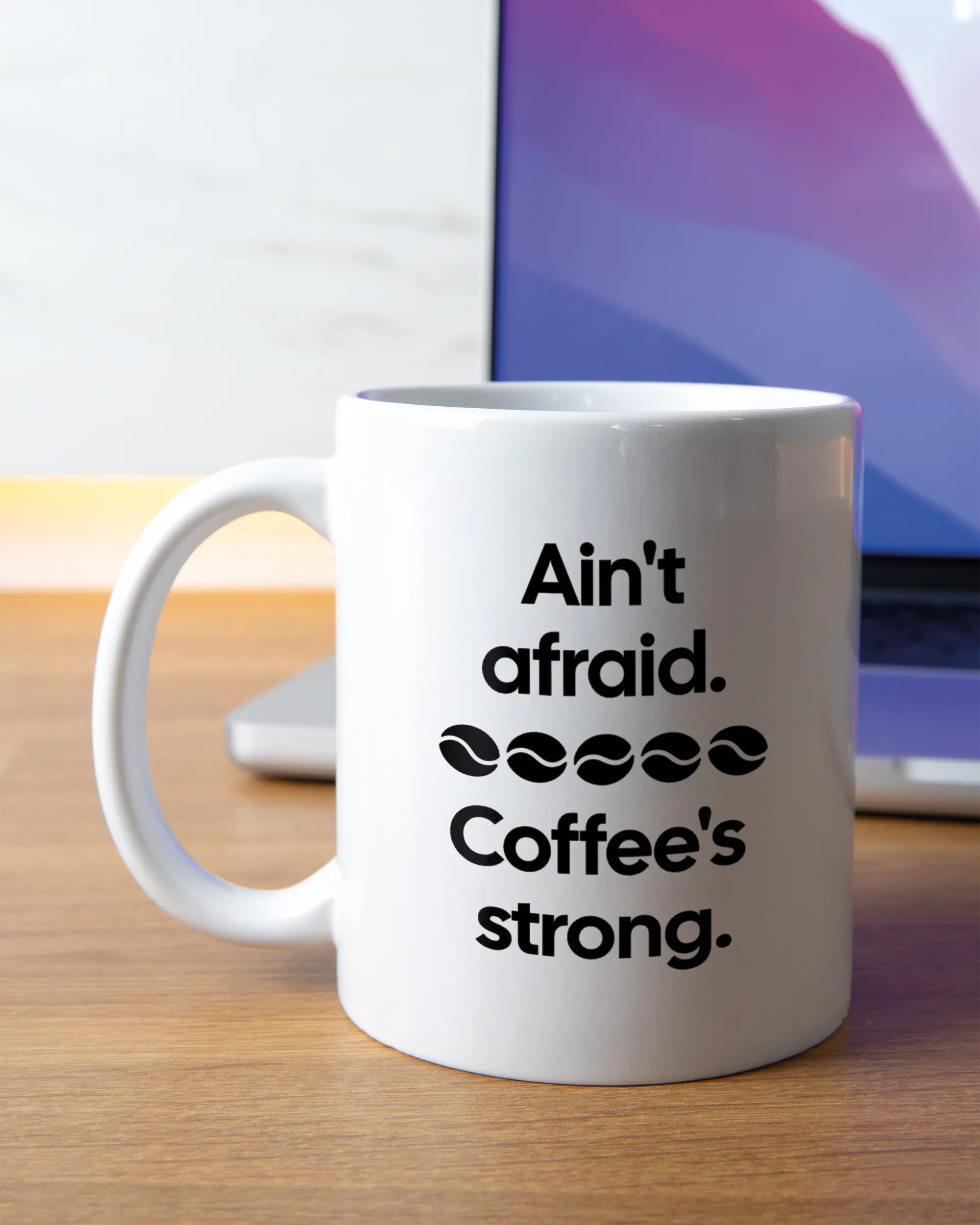 Homeoffice Aufnahme der linken Seite der beidseitig bedruckten Keramiktasse von Maondo mit dem Design Coffee is strong in der Farbe White