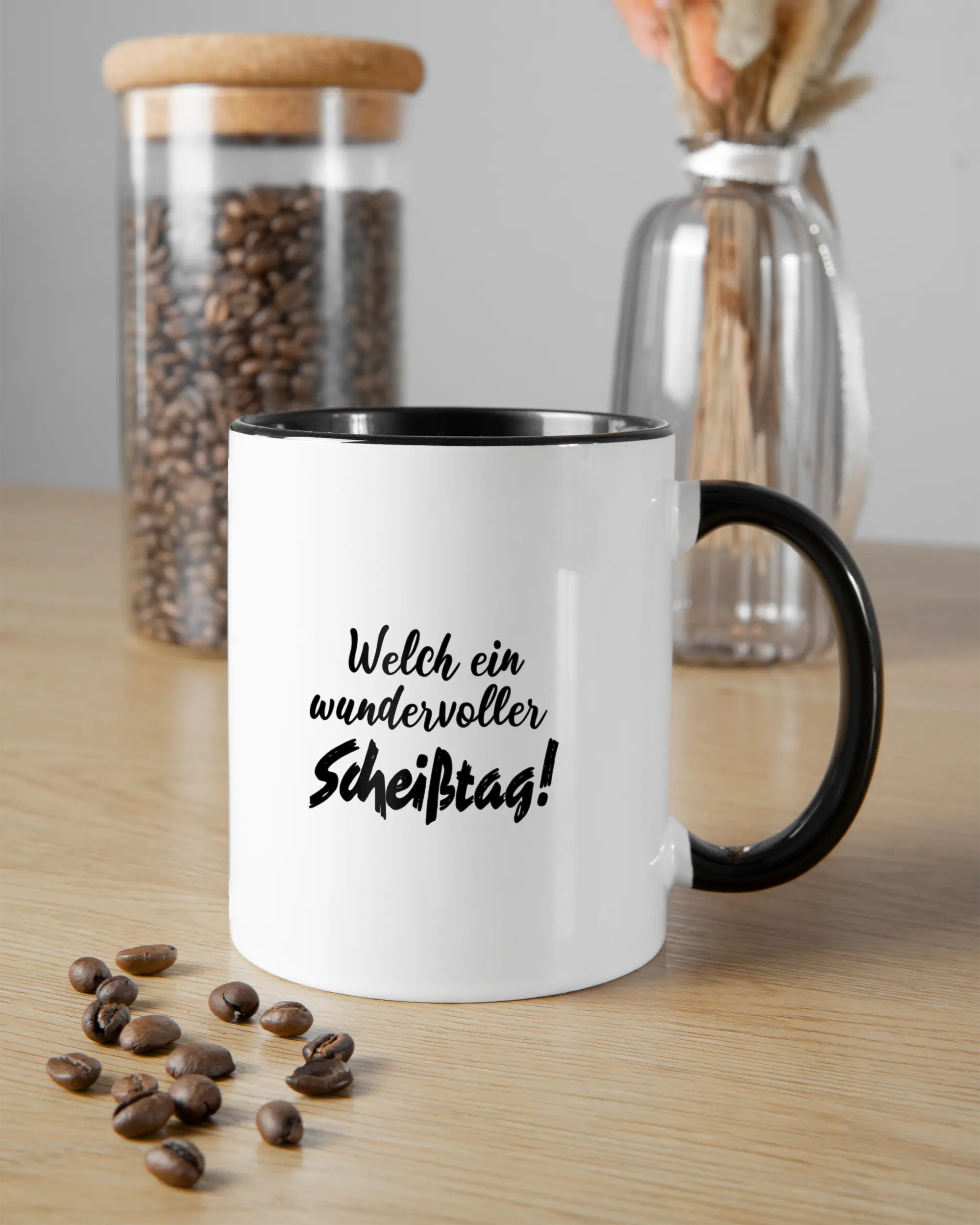 Essenstisch Aufnahme der beidseitig bedruckten Keramik Tasse von Maondo mit dem Design Wundervoller Scheißtag in der Farbe Schwarz-Weiß