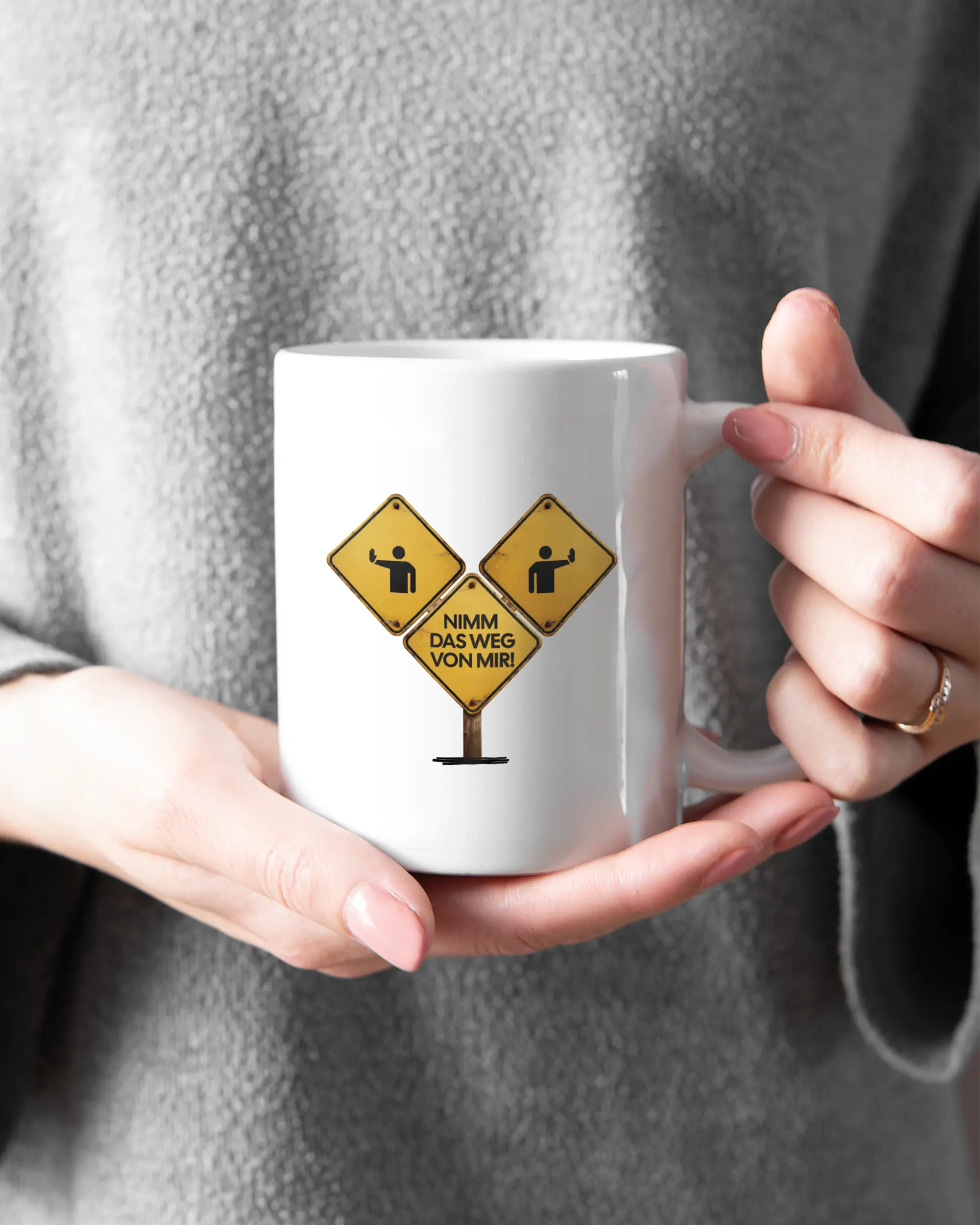 Rechte Seite der beidseitig bedruckten Keramiktasse von Maondo mit dem Design Schutzschild in der Farbe White gehalten von Frauenhänden