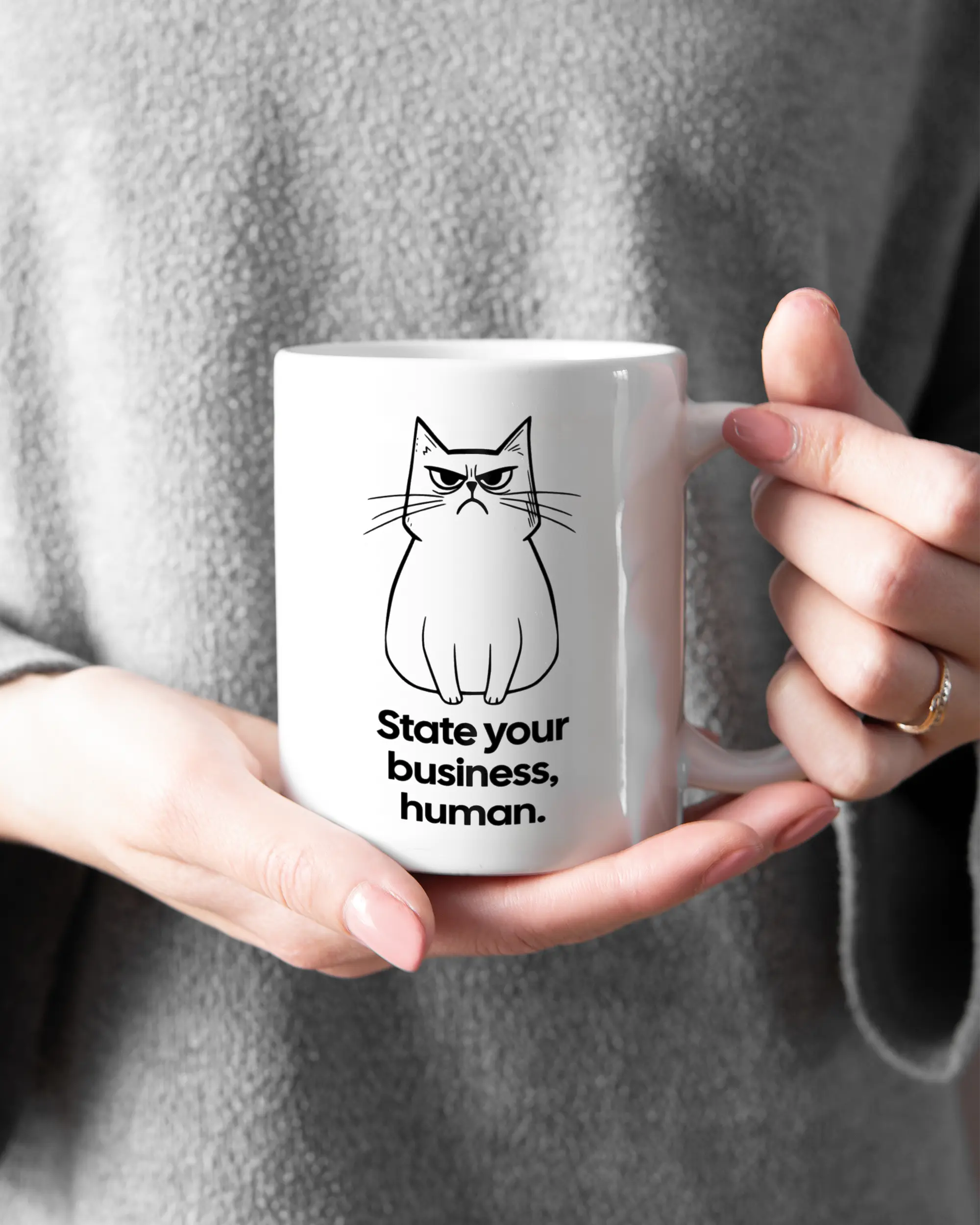 Rechte Seite der beidseitig bedruckten Keramiktasse von Maondo mit dem Design Grumpy Purr in der Farbe White gehalten von Frauenhänden