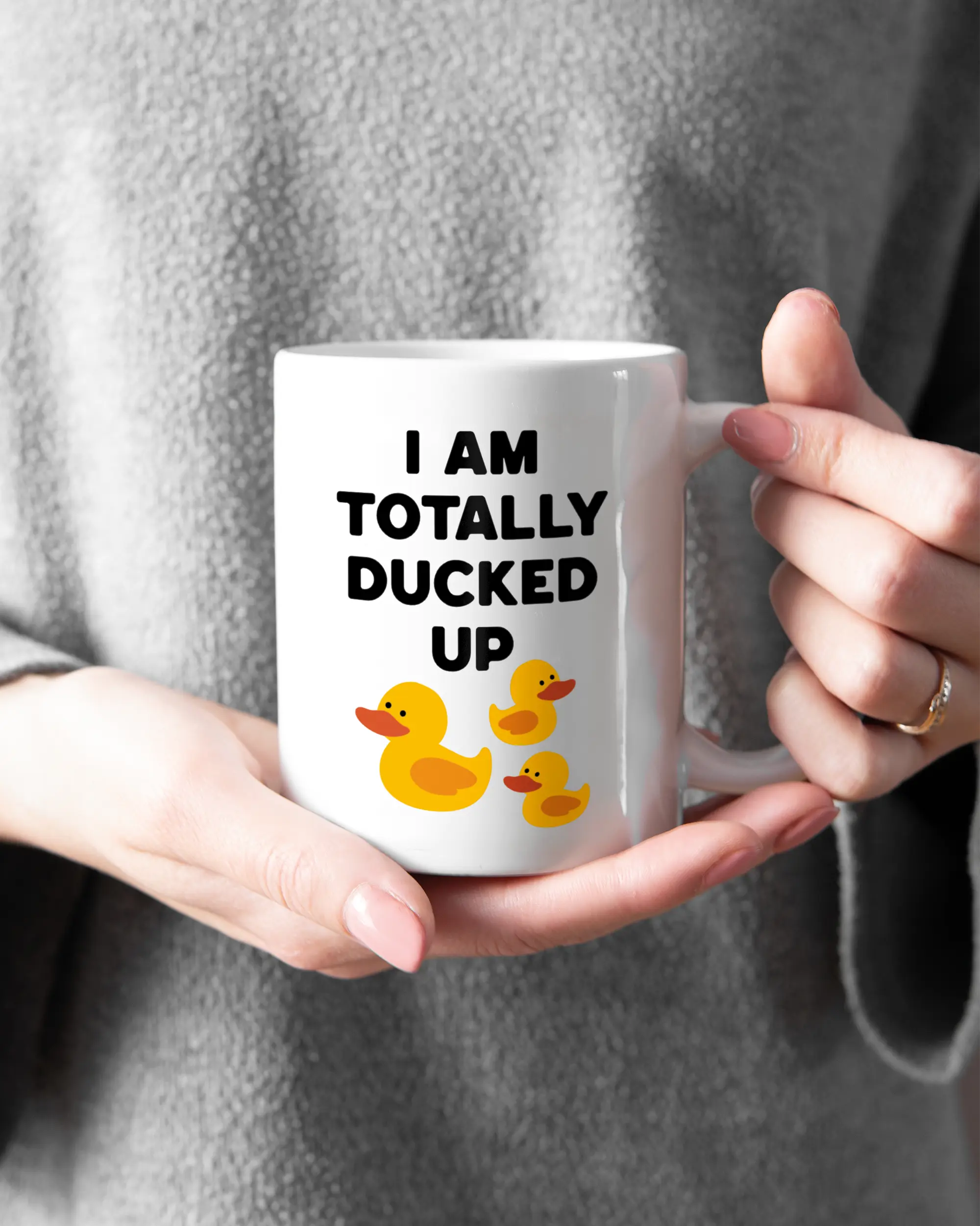 Rechte Seite der beidseitig bedruckten Keramiktasse von Maondo mit dem Design Ducked Up in der Farbe White gehalten von Frauenhänden