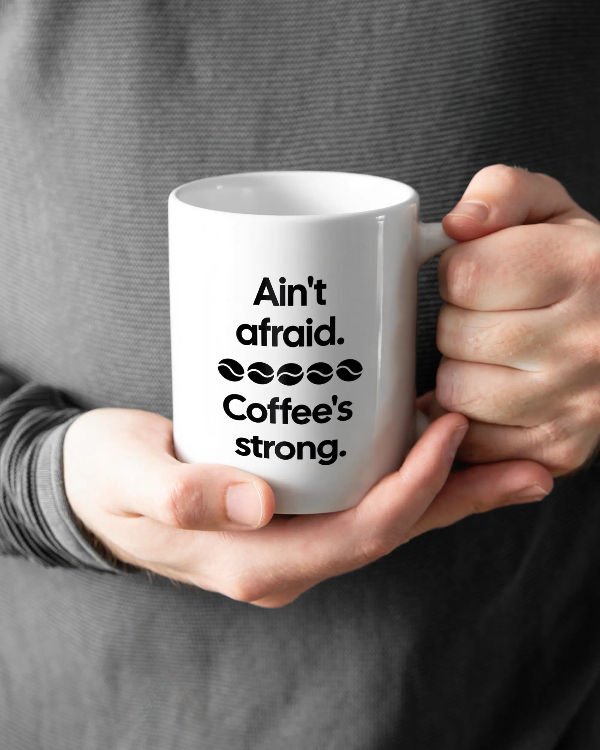 Rechte Seite der beidseitig bedruckten Keramiktasse von Maondo mit dem Design Coffee is strong in der Farbe White gehalten von Männerhänden