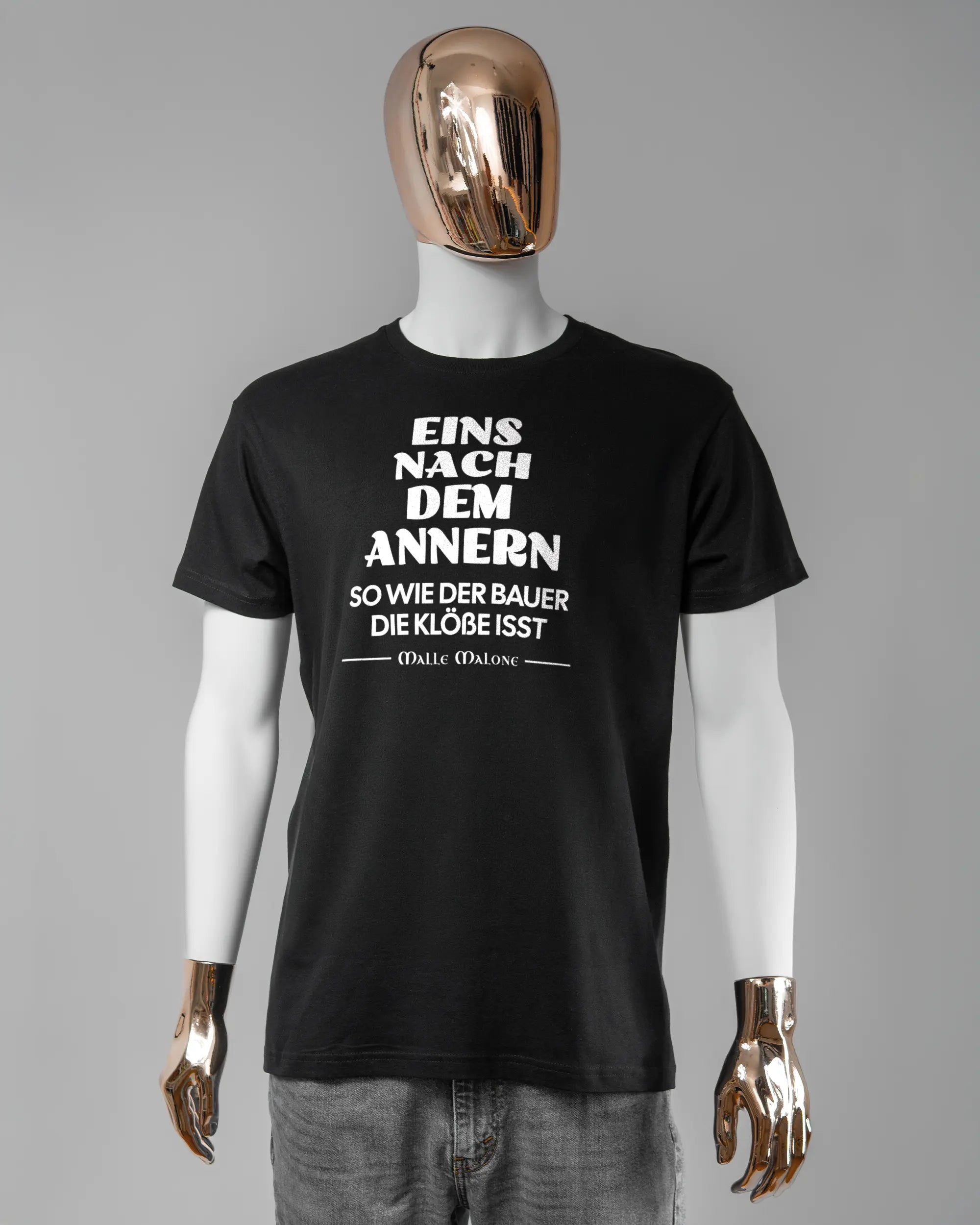Vorderseite des Basic Unisex T-Shirt Soft von Maondo mit dem Design Eins nach dem Annern in der Farbe Black und in der Größe L getragen von einer maskulinen Puppe