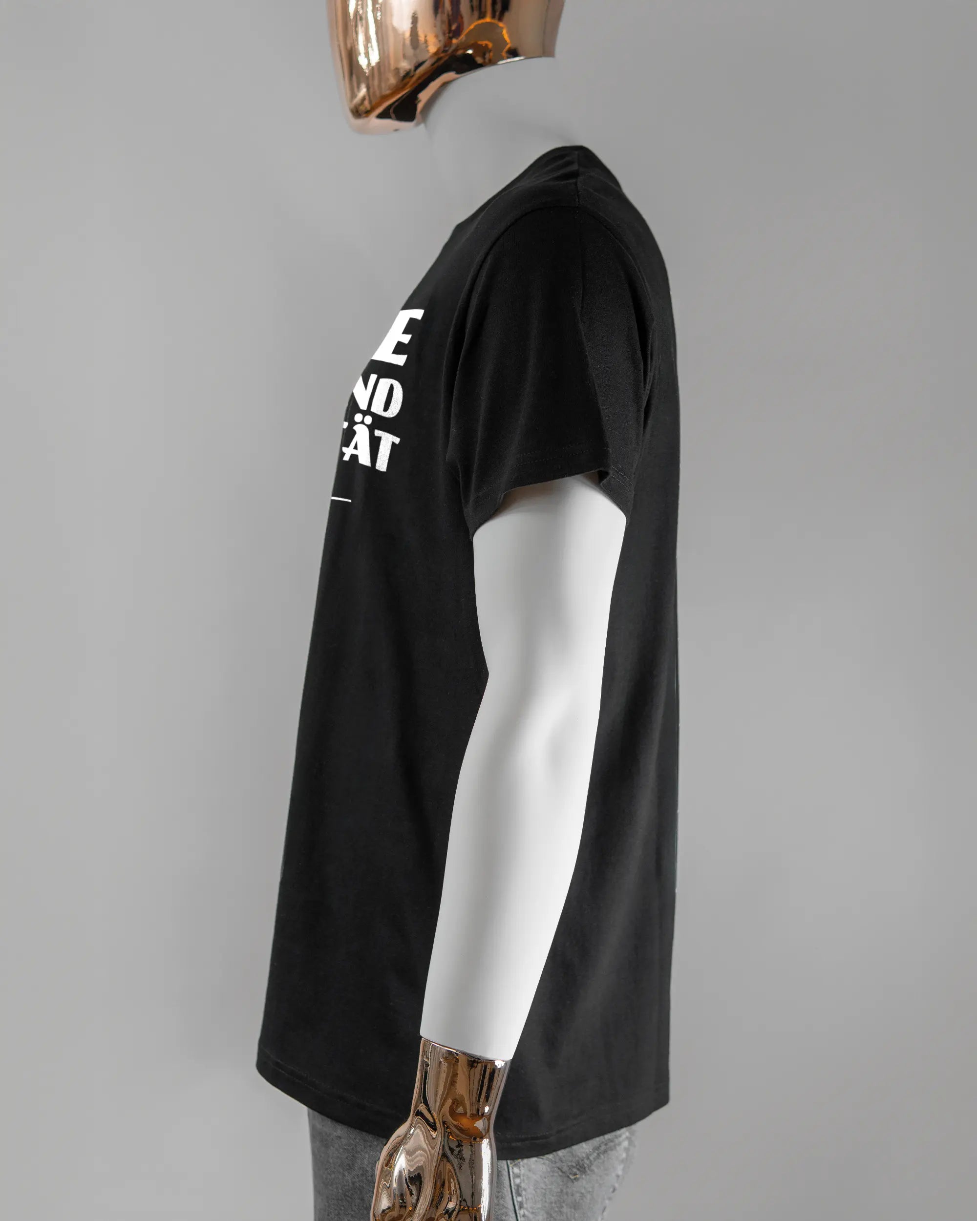 Seitenansicht des Basic Unisex T-Shirt Soft von Maondo mit dem Design Keine Eile vorne in der Farbe Black und in der Größe L getragen von einer maskulinen Puppe