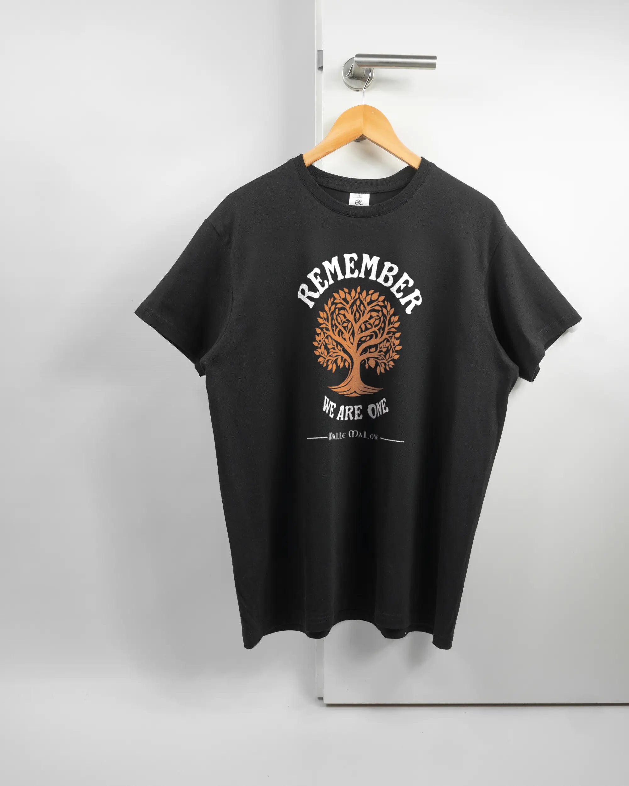 Vorderseite des Basic Unisex T-Shirt Soft von Maondo mit dem Design We are one in der Farbe Black und in der Größe L auf einem Bügel an der Türklinke aufgehängt