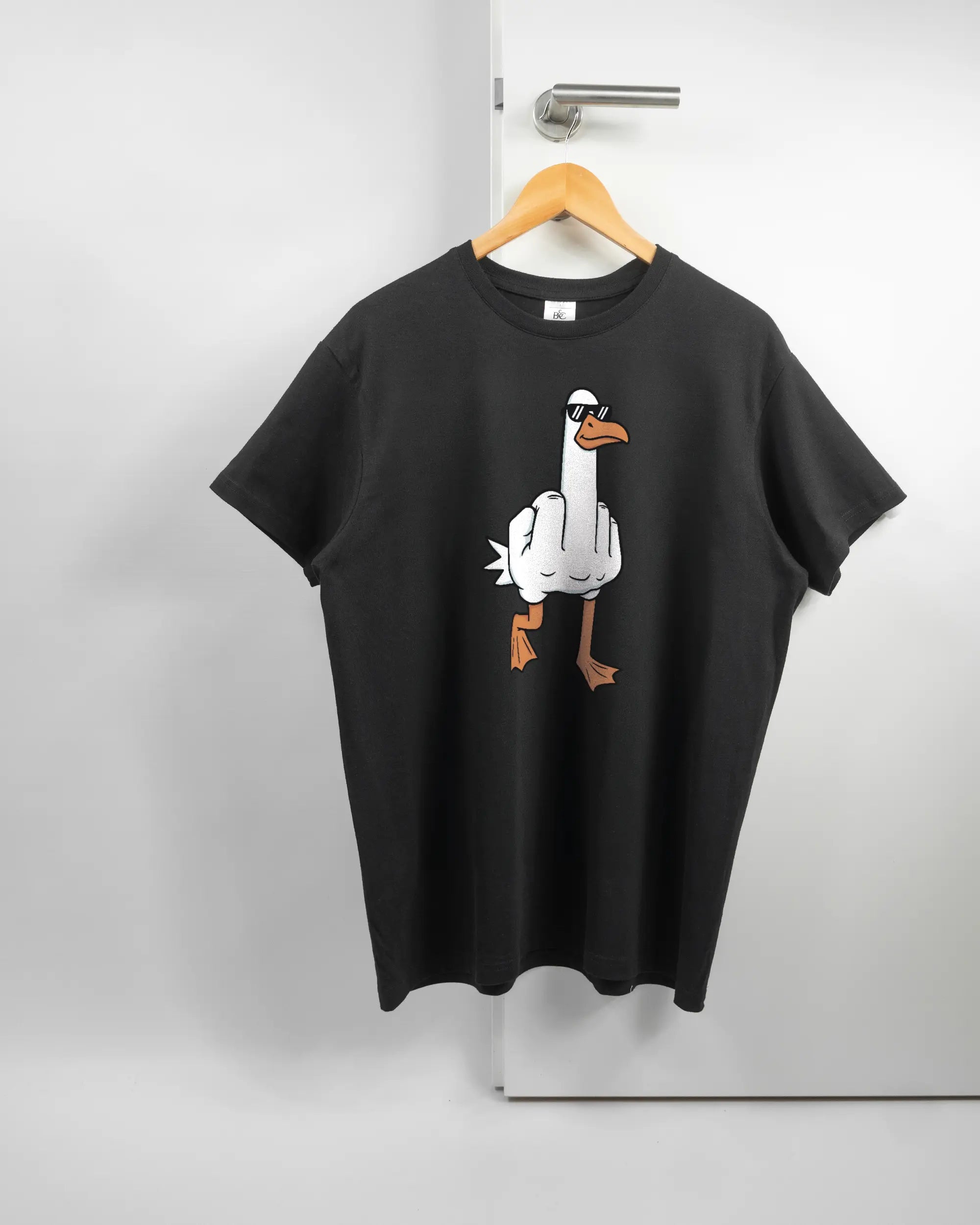 Vorderseite des Basic Unisex T-Shirt Soft von Maondo mit dem Design I give a duck in der Farbe Black und in der Größe L auf einem Bügel an der Türklinke aufgehängt