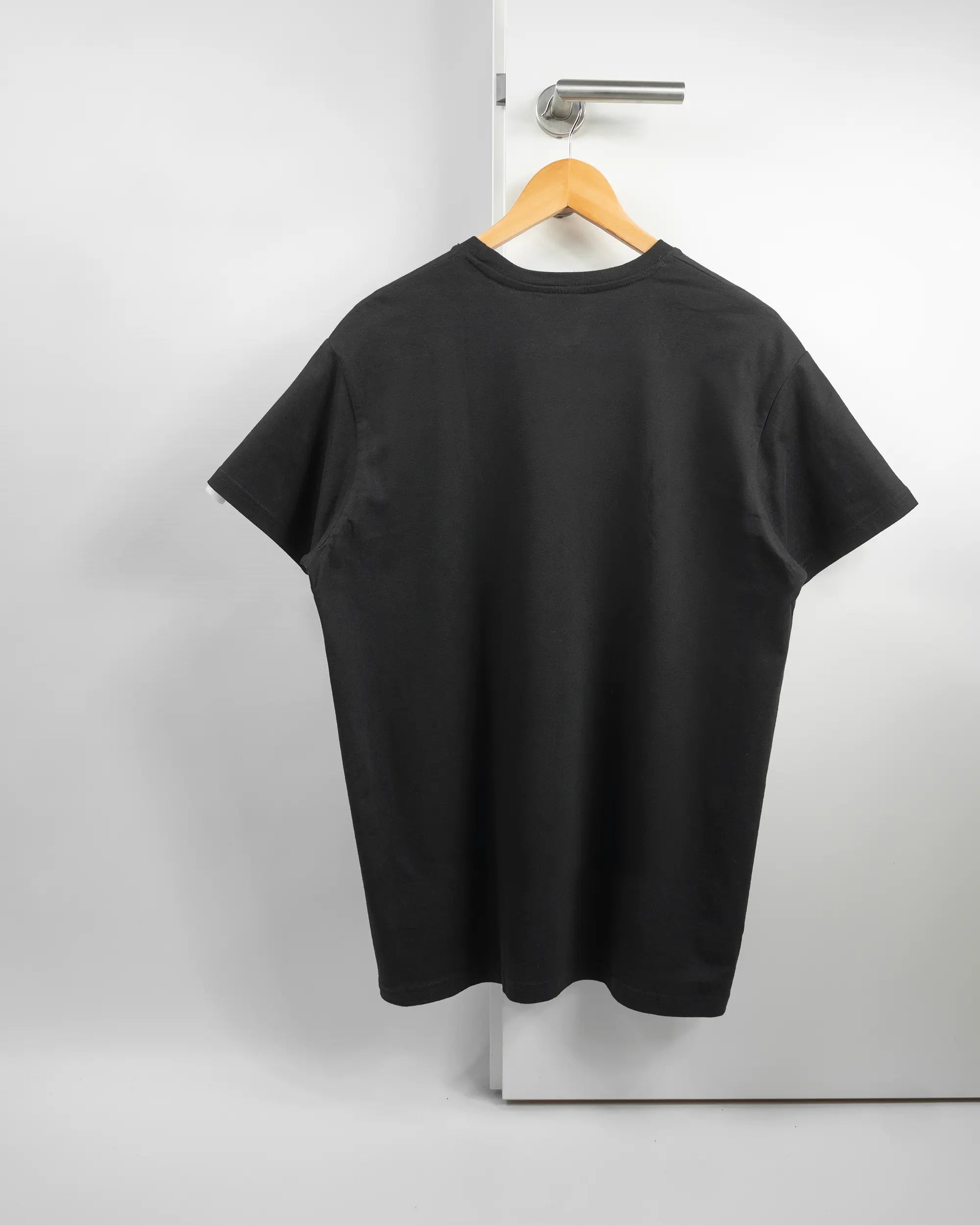 Rückseite des Basic Unisex T-Shirt Soft von Maondo ohne Motiv in der Farbe Black und in der Größe L auf einem Bügel an der Türklinke aufgehängt