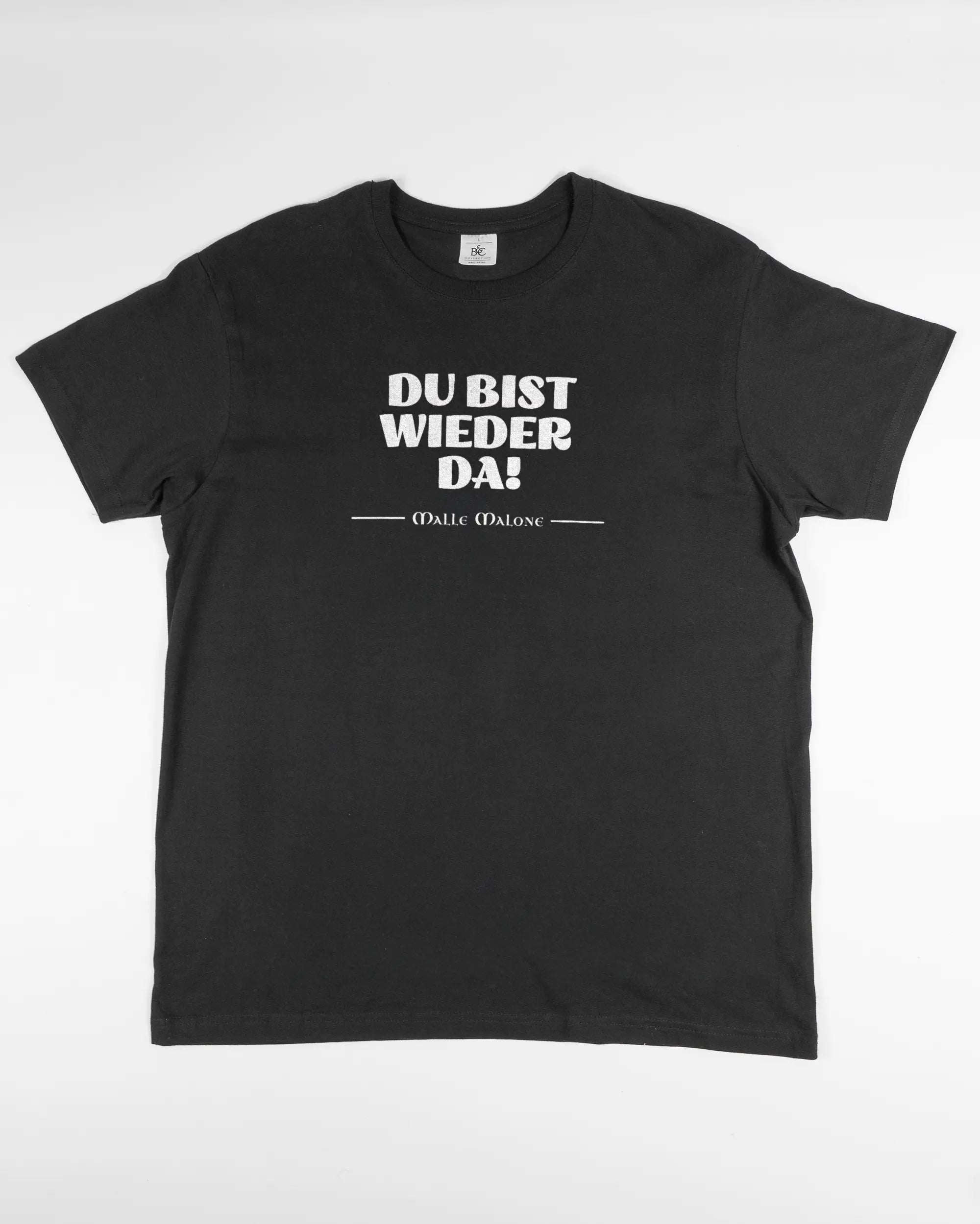 Vorderseite des Basic Unisex T-Shirt Soft von Maondo mit dem Design Wieder da in der Farbe Black und in der Größe L flach auf den Boden gelegt