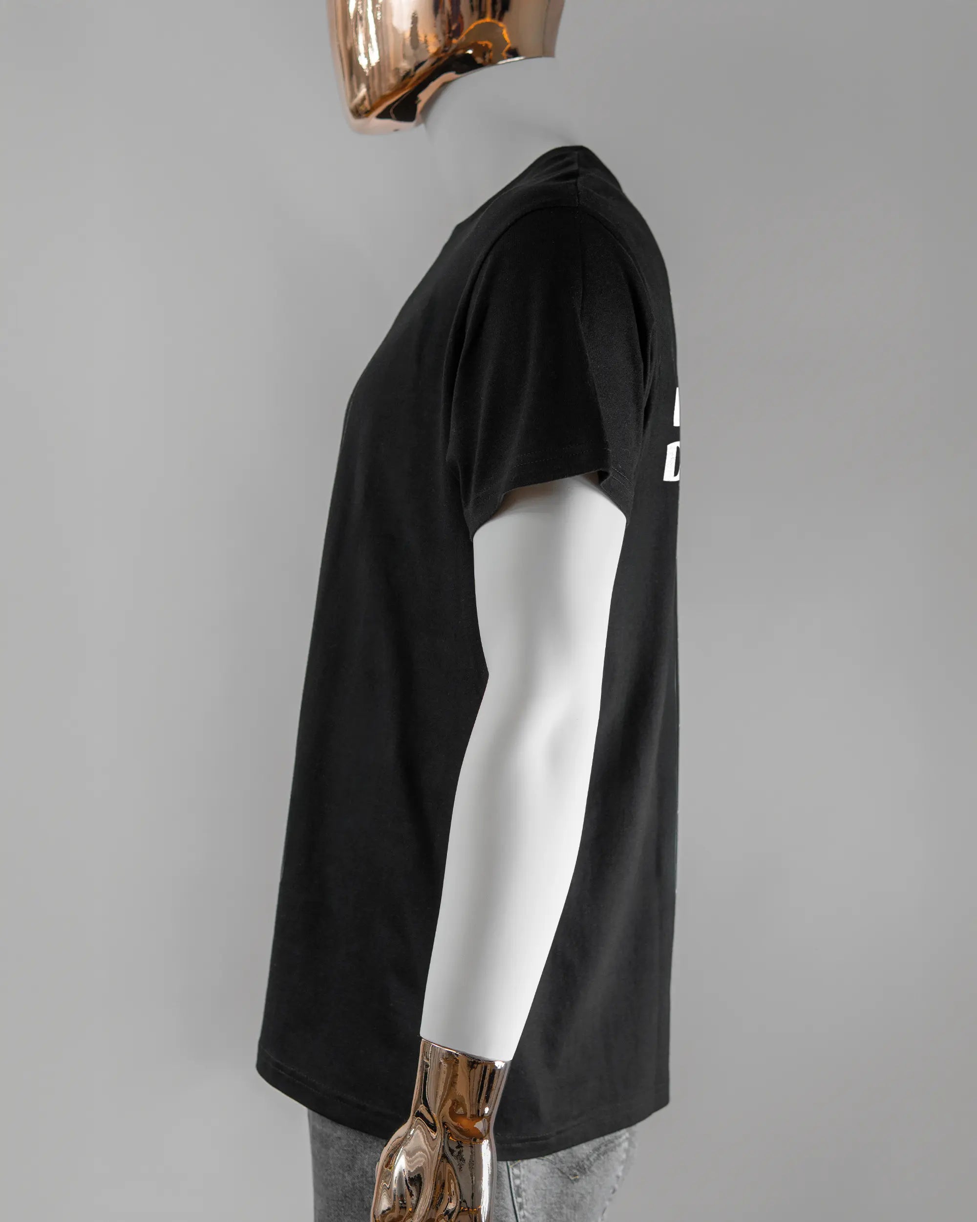 Seitenansicht des Basic Unisex T-Shirt Soft von Maondo mit dem Design Keine Eile hinten in der Farbe Black und in der Größe L getragen von einer maskulinen Puppe
