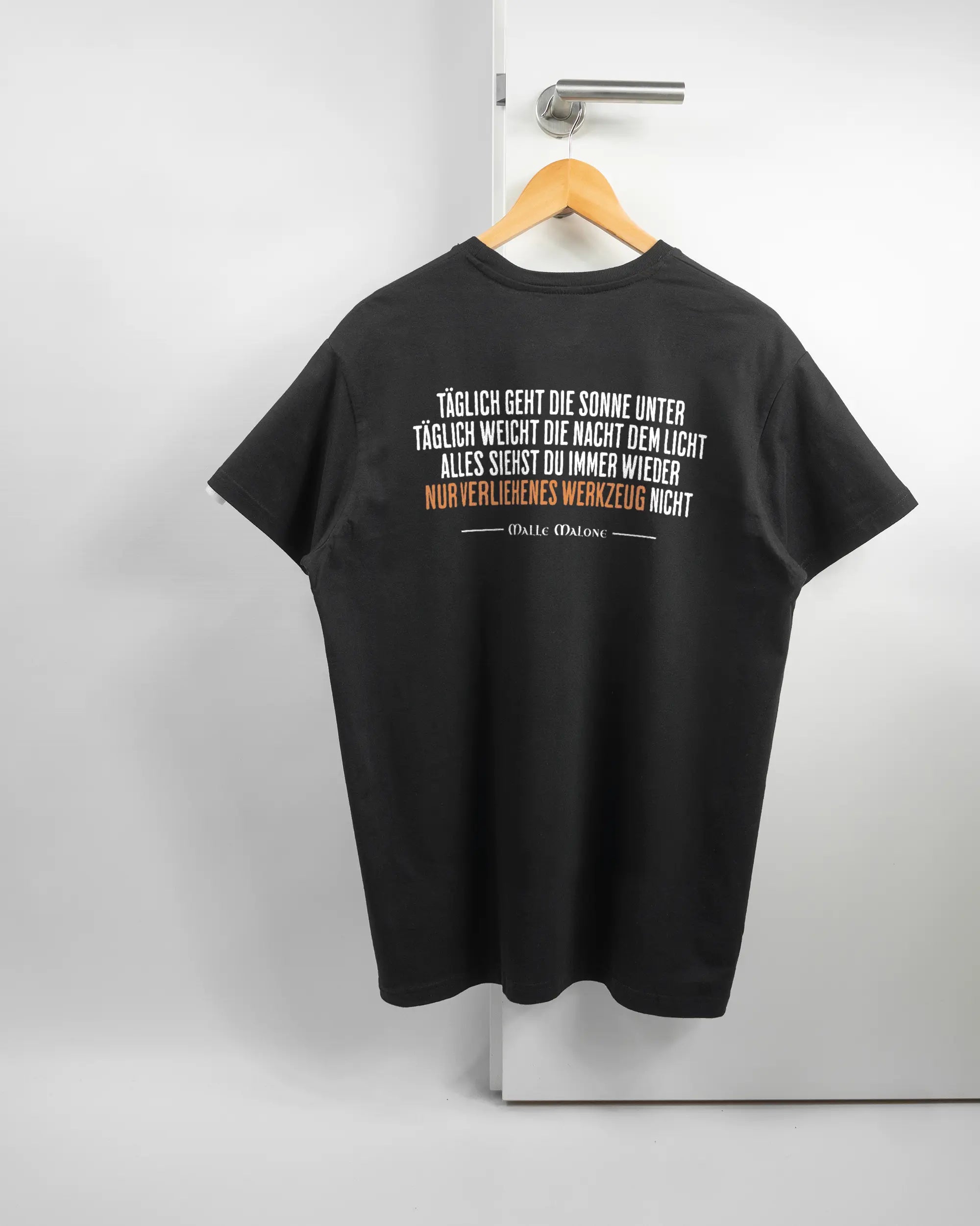Rückseite des Basic Unisex T-Shirt Soft von Maondo mit dem Design Wegzeug in der Farbe Black und in der Größe L auf einem Bügel an der Türklinke aufgehängt