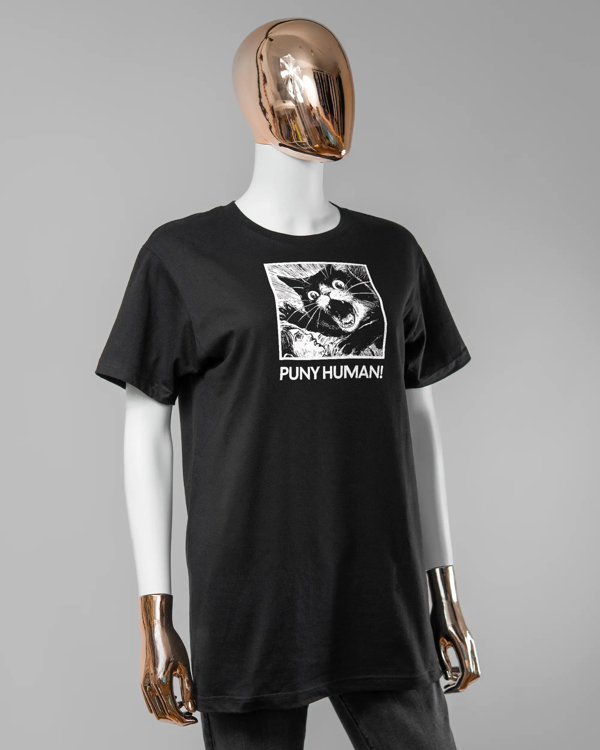 Vorderseite des Basic Unisex T-Shirt Soft von Maondo mit dem Design Puny Human in der Farbe Black und in der Größe S getragen von einer femininen Puppe