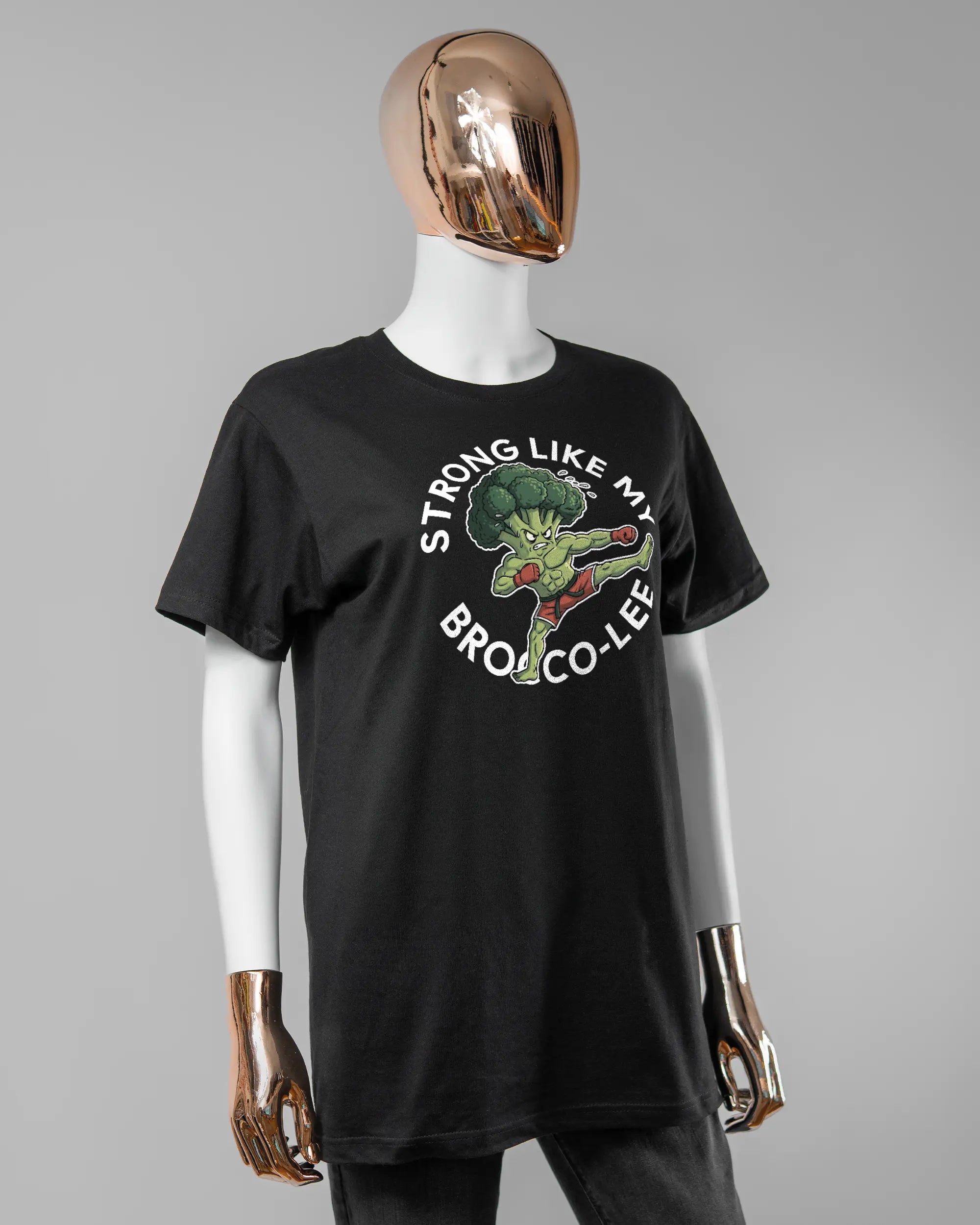 Vorderseite des Basic Unisex T-Shirt Soft von Maondo mit dem Design Brocco-Lee in der Farbe Black und in der Größe S getragen von einer femininen Puppe