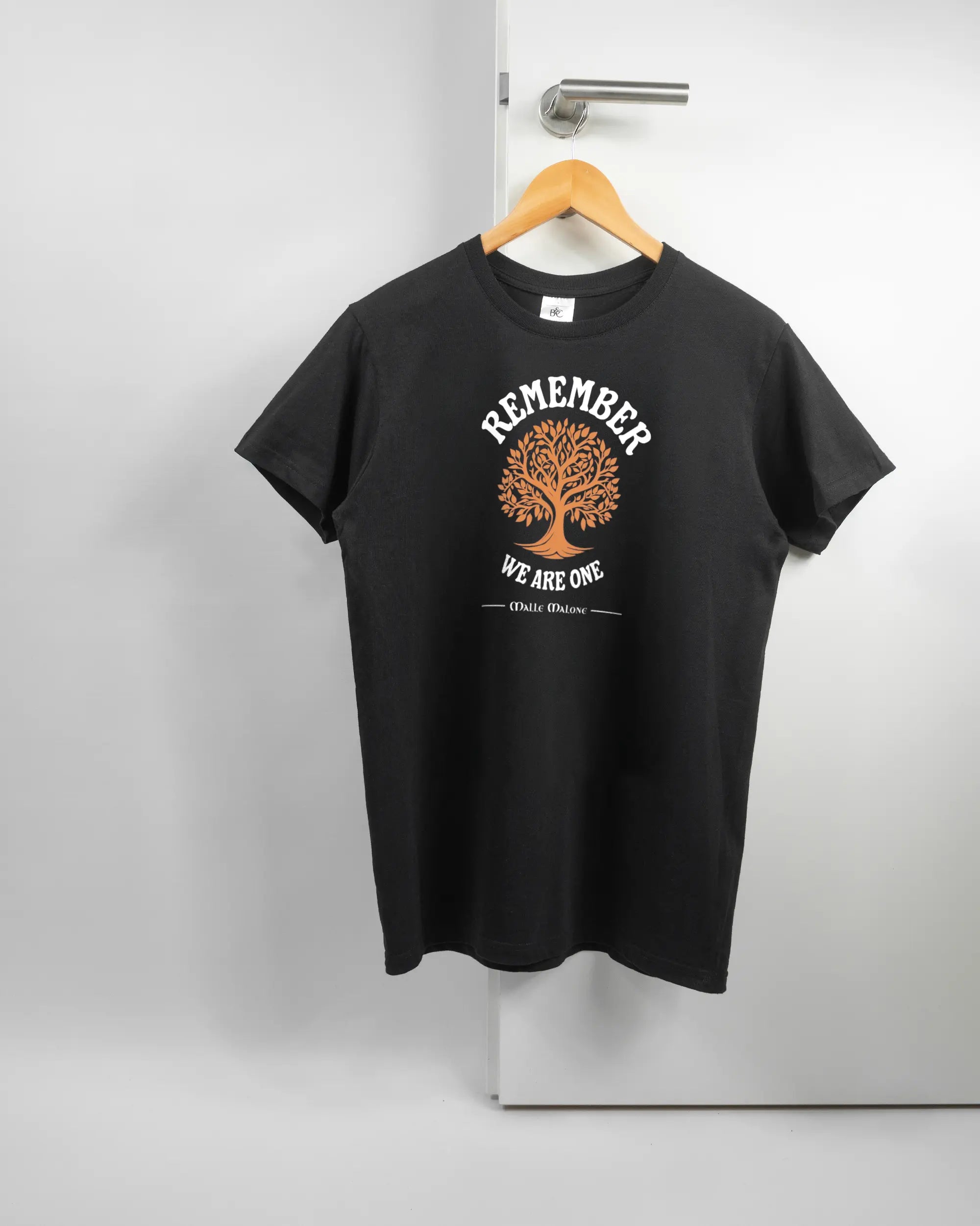 Vorderseite des Basic Unisex T-Shirt Soft von Maondo mit dem Design We are one in der Farbe Black und in der Größe S auf einem Bügel an der Türklinke aufgehängt