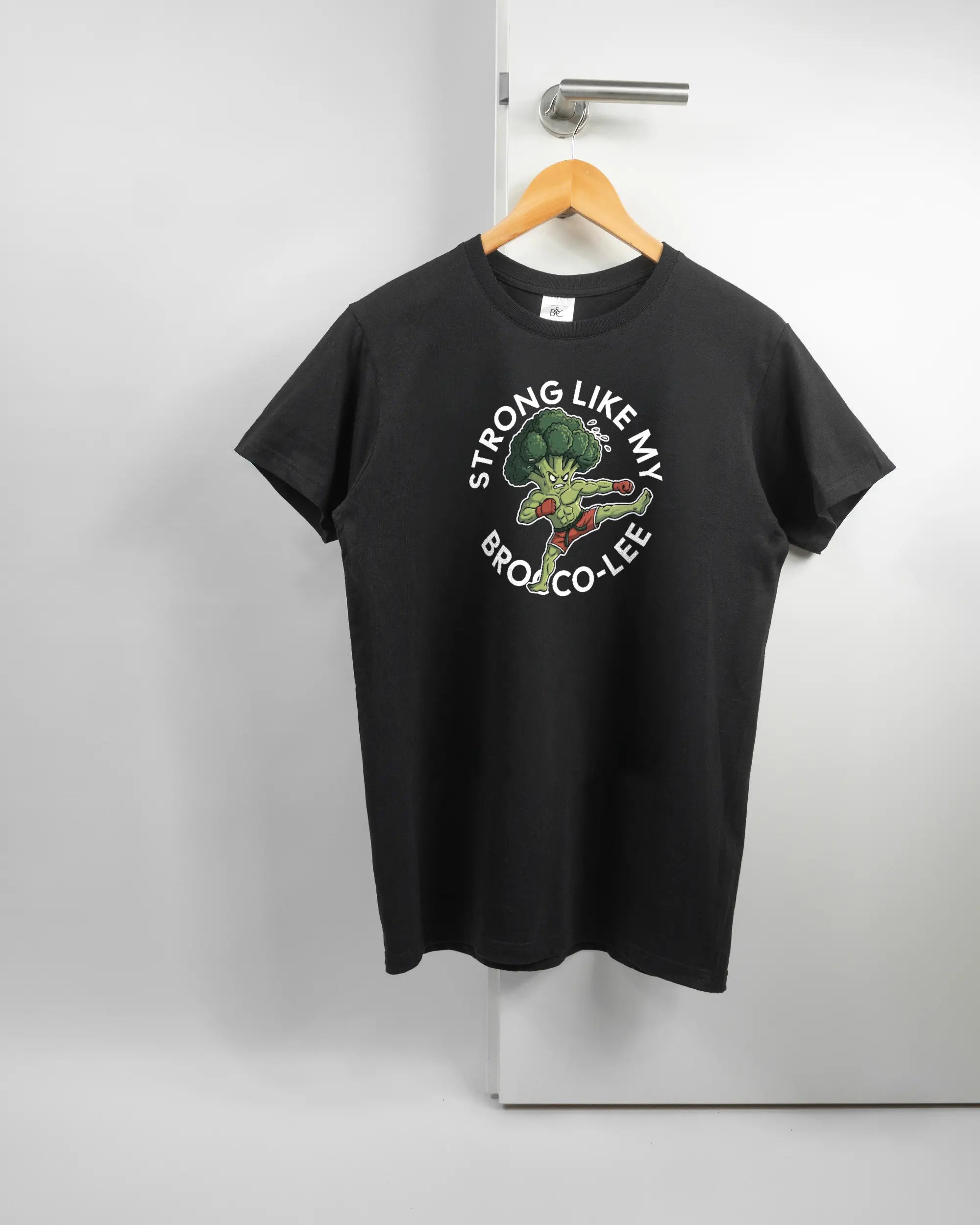 Vorderseite des Basic Unisex T-Shirt Soft von Maondo mit dem Design Brocco-Lee in der Farbe Black und in der Größe S auf einem Bügel an der Türklinke aufgehängt