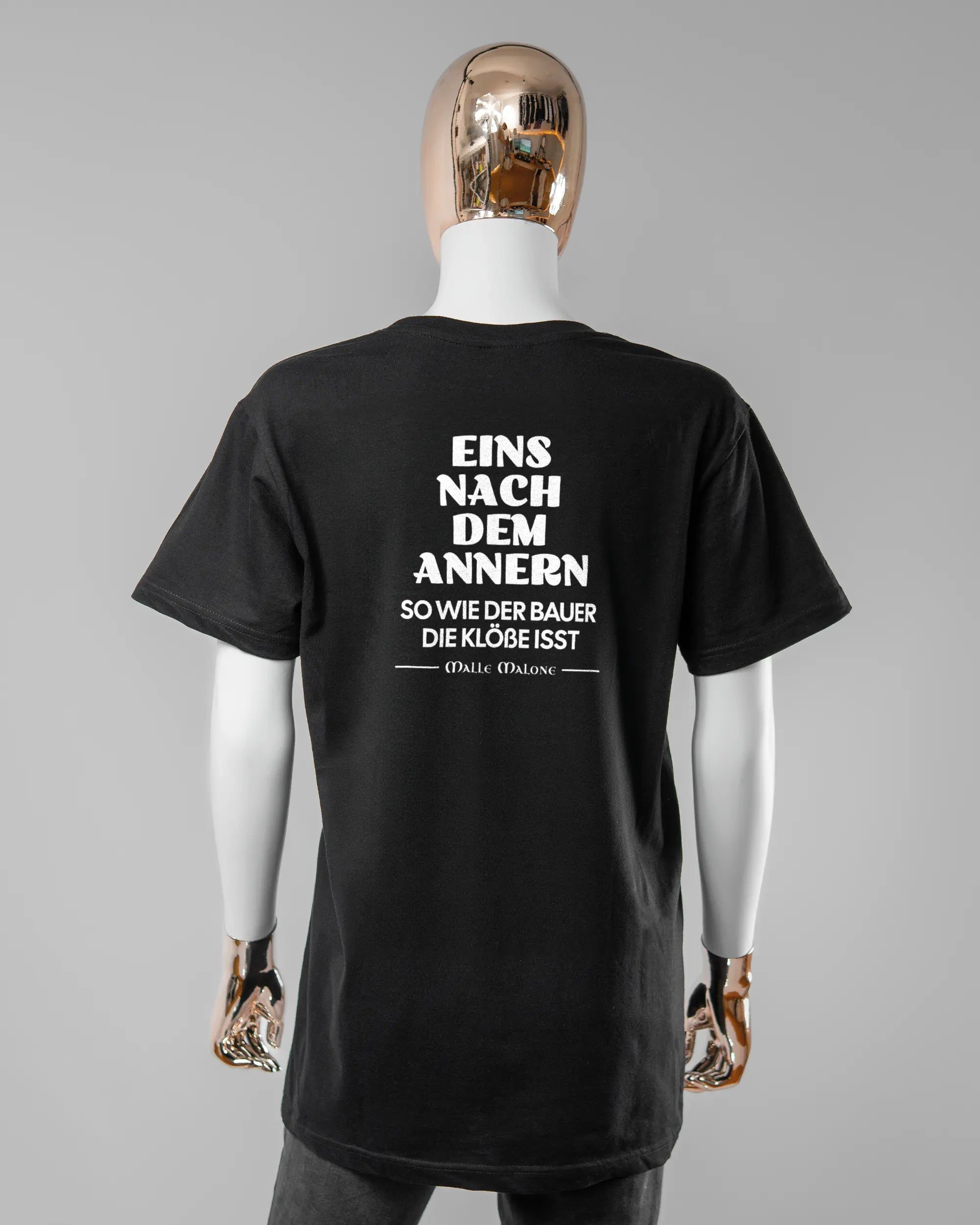 Rückseite des Basic Unisex T-Shirt Soft von Maondo mit dem Design Eins nach dem Annern in der Farbe Black und in der Größe S getragen von einer femininen Puppe