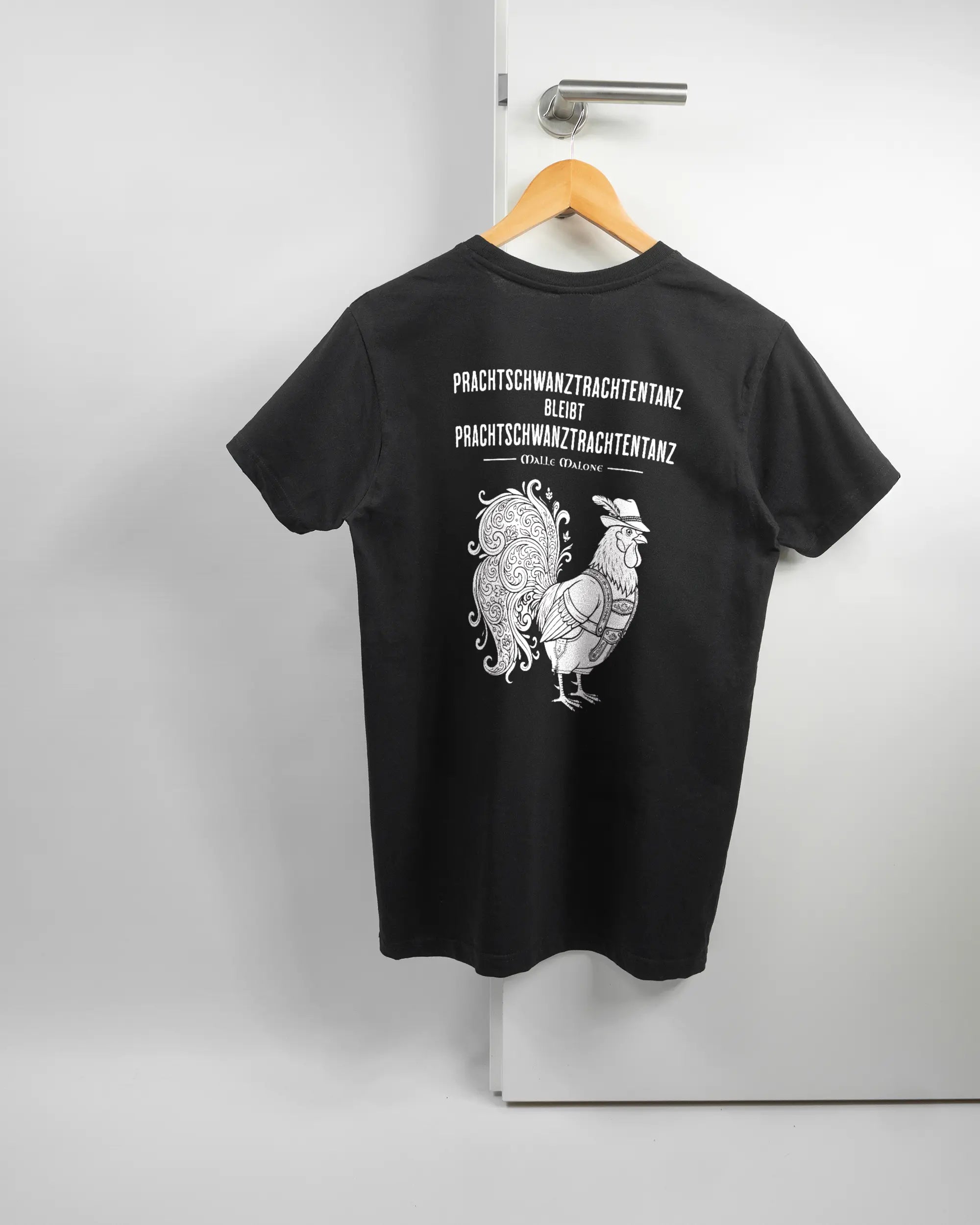 Rückseite des Basic Unisex T-Shirt Soft von Maondo mit dem Design Trachtentanz in der Farbe Black und in der Größe S auf einem Bügel an der Türklinke aufgehängt