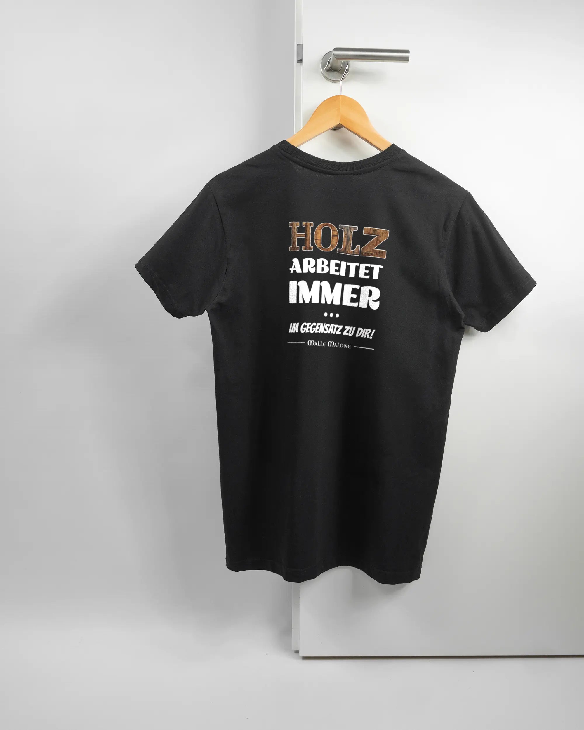Rückseite des Basic Unisex T-Shirt Soft von Maondo mit dem Design Holzarbeit in der Farbe Black und in der Größe S auf einem Bügel an der Türklinke aufgehängt