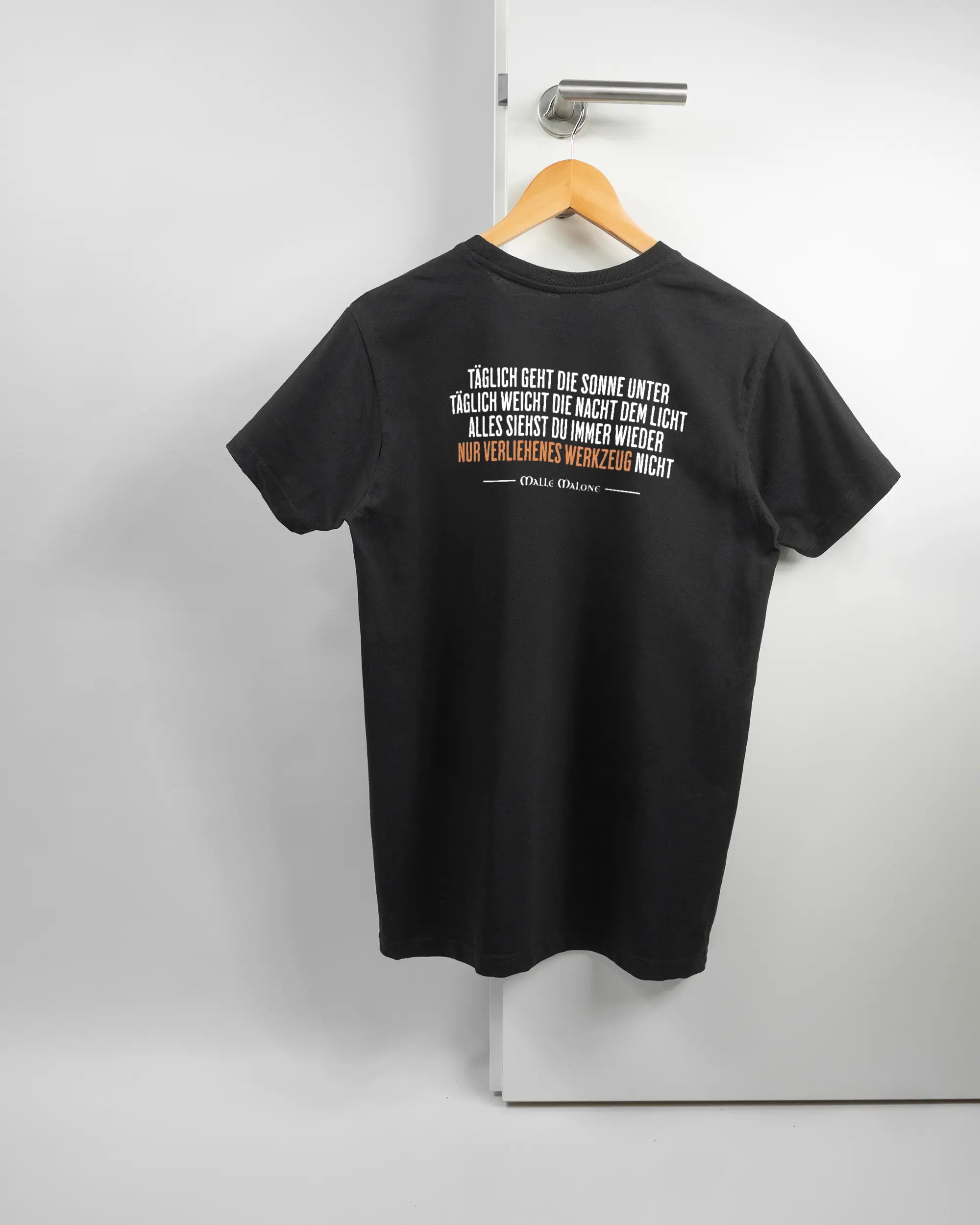 Rückseite des Basic Unisex T-Shirt Soft von Maondo mit dem Design Wegzeug in der Farbe Black und in der Größe S auf einem Bügel an der Türklinke aufgehängt