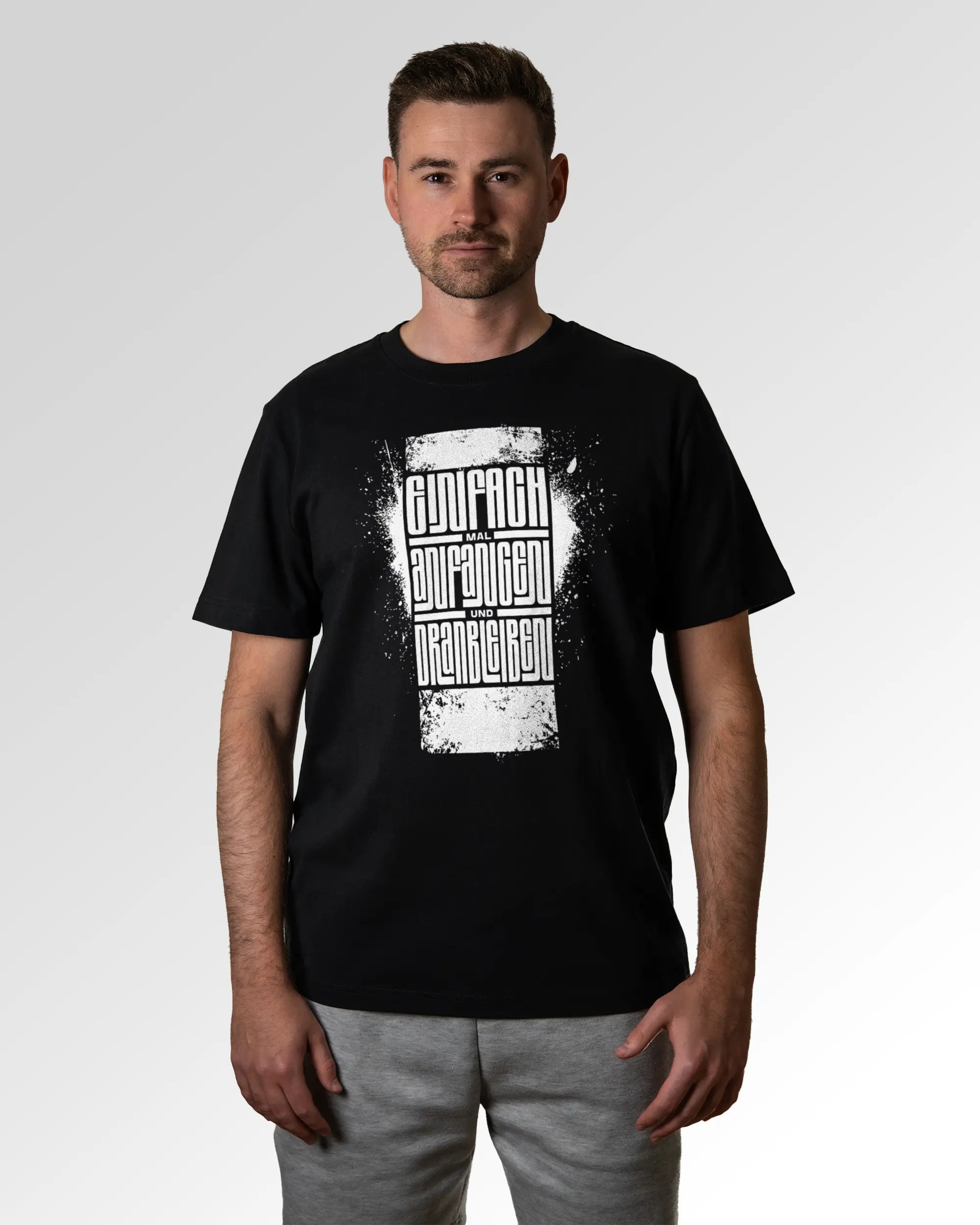 Primärer Modelshot der Druckseite des Organic Unisex T-Shirts von Maondo im Heavy Fit mit dem Design Einfach Anfangen in der Farbe Black