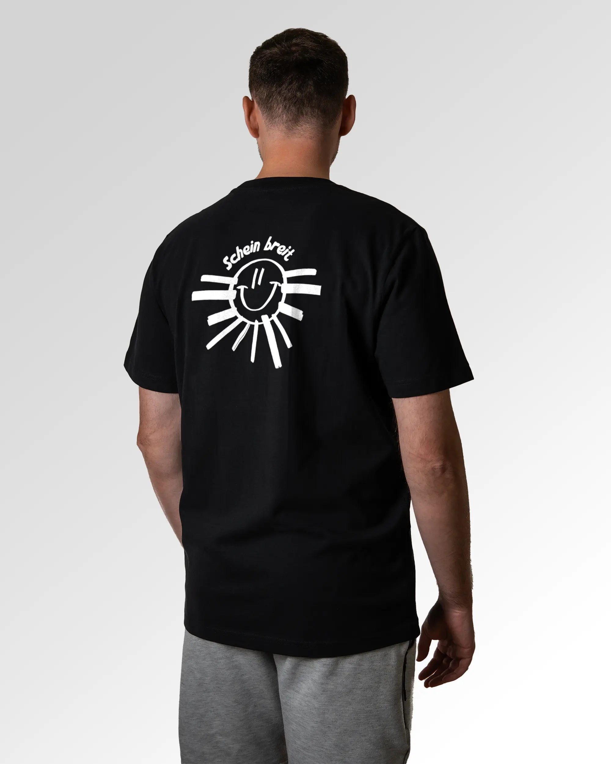 Primärer Modelshot der Druckseite des Organic Unisex T-Shirts von Maondo im Heavy Fit mit dem Design Schein Breit in der Farbe Black