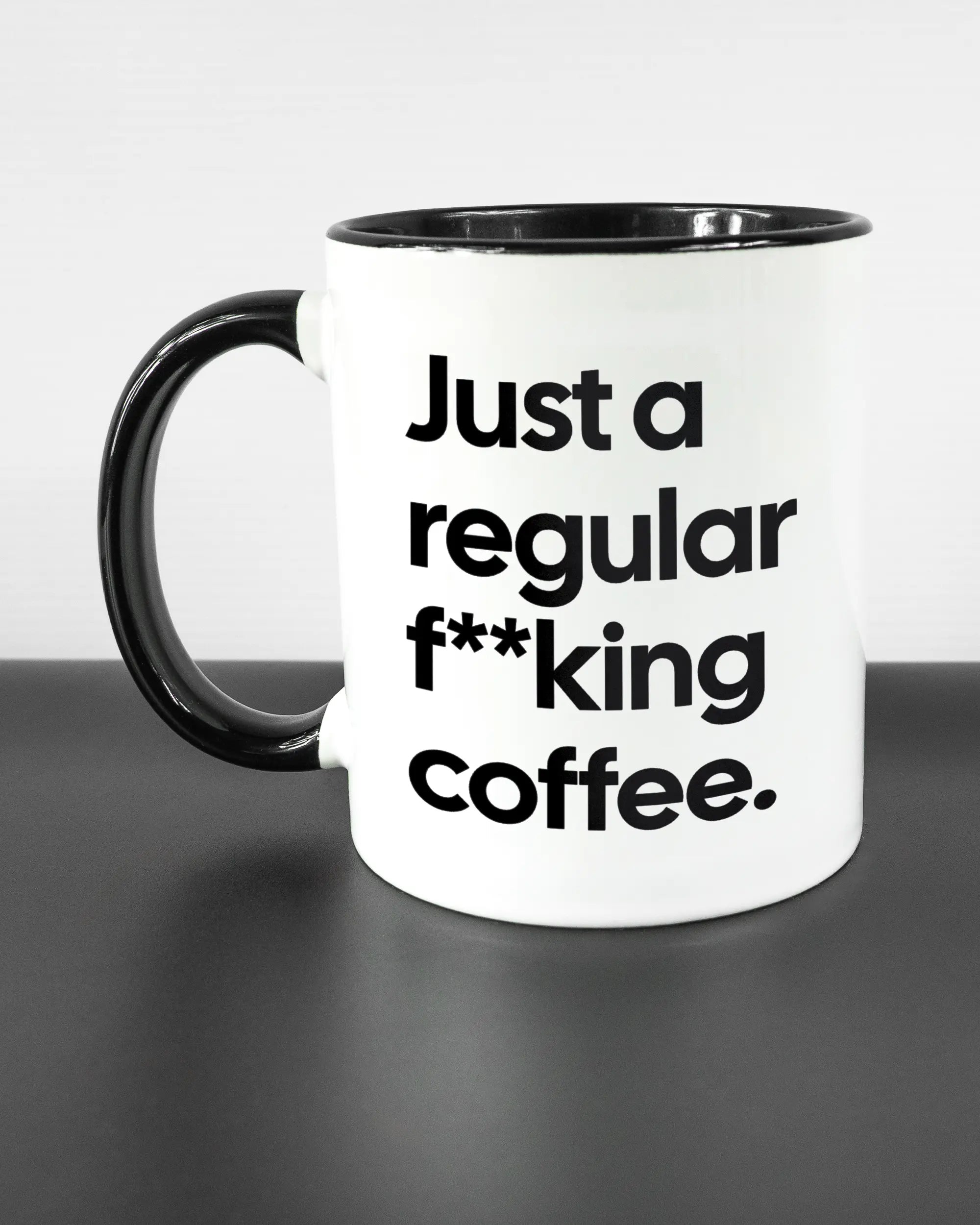 Titelbild, das die linke Seite der beidseitig bedruckten Keramiktasse von Maondo mit dem Design Regular Coffee in der Farbe Duotone auf einem Holztisch zeigt